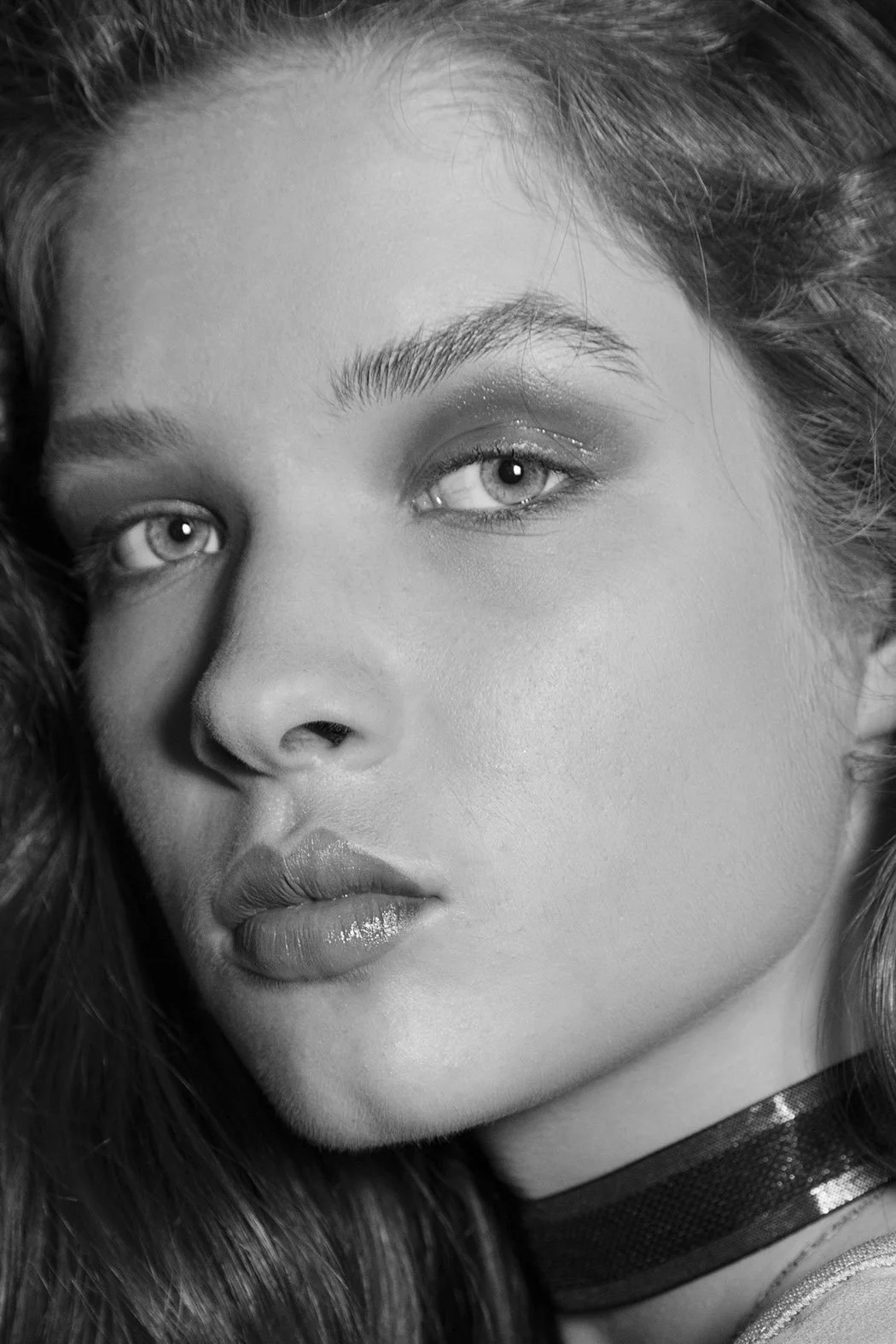 Ritratto in bianco e nero di una donna con capelli ricci, sopracciglia arcuate, occhi chiari, labbra piene e un collare nero intorno al collo.