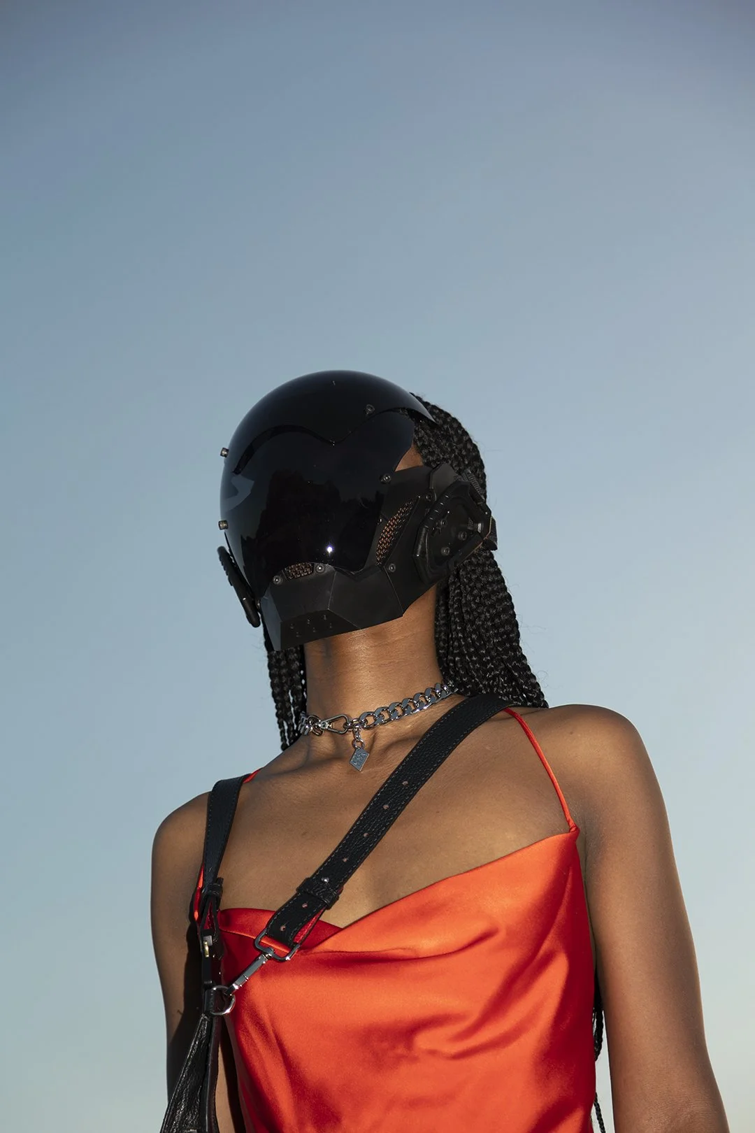 Donna con capelli a treccia, indossa un casco nero e una maglia rossa