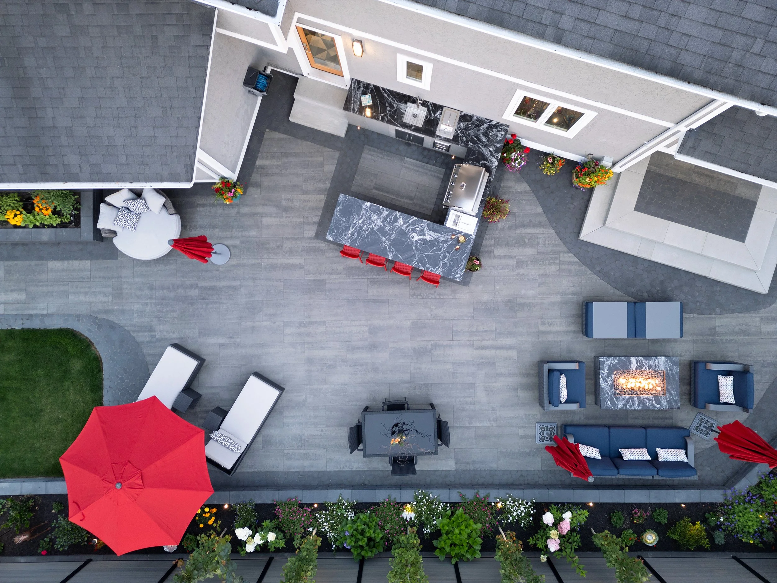 Aerial view of a modern outdoor patio area with a seating arrangement, table with decorations, potted flowers, and umbrellas.