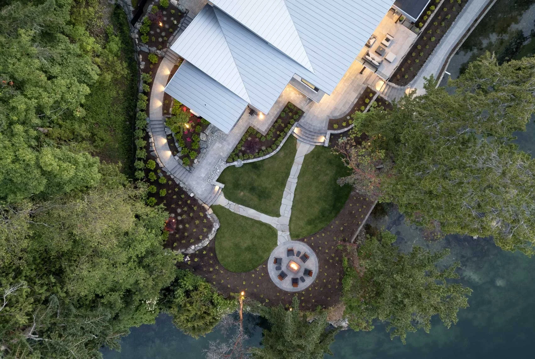 Project photo of a drone shot overlooking a beautiful home on the ocean with rock work featuring firepit, walkway and stone walls