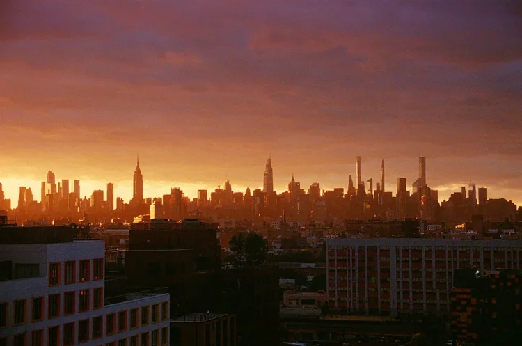 City skyline at sunset with silhouette of skyscrapers and a colorful sky.