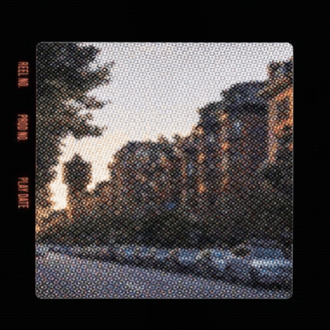 City street with parked cars and brick buildings under a sunset sky.