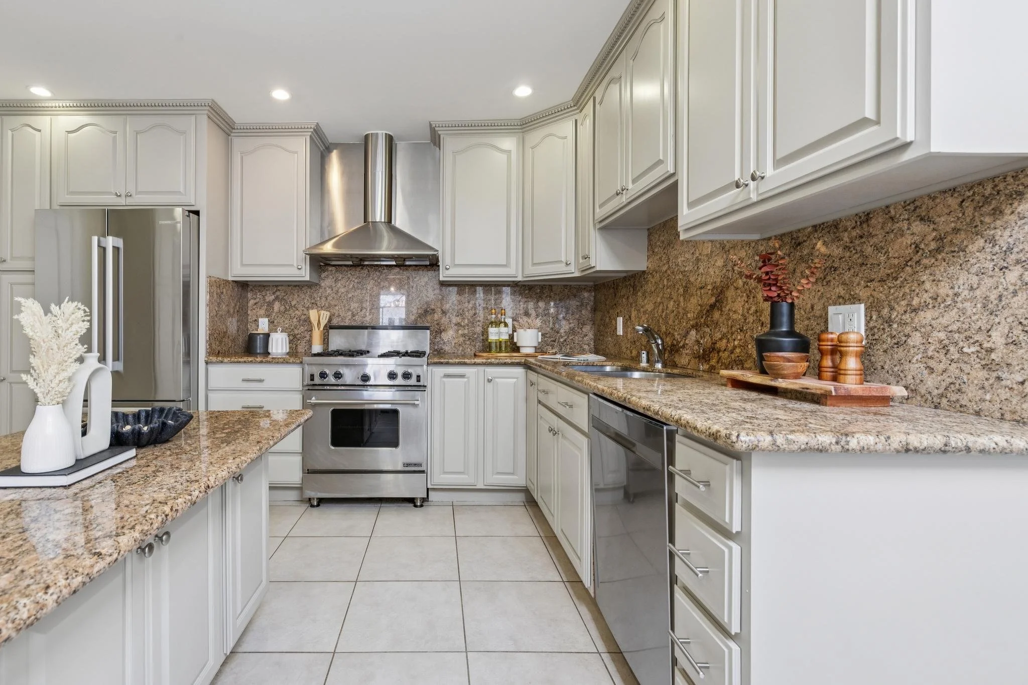 Kitchen with white cabinets, granite countertops, stainless steel appliances, and a beige tiled floor.