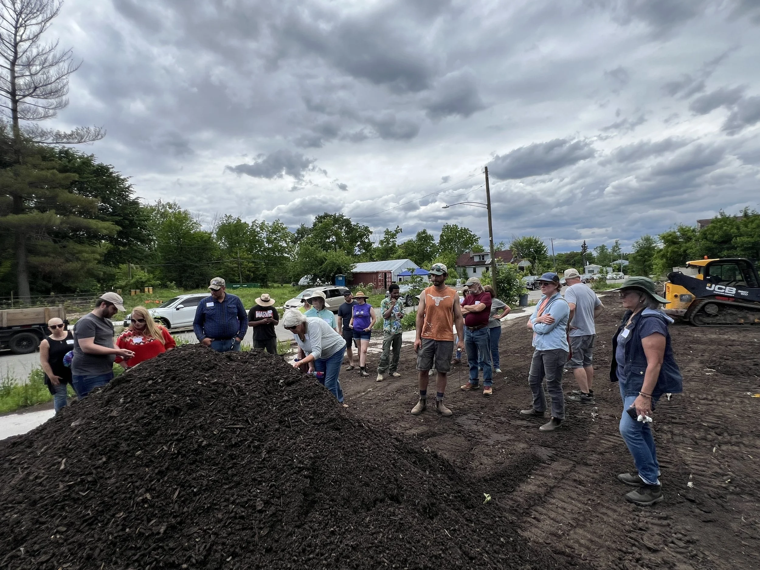 A group of people inspecting a compost pile