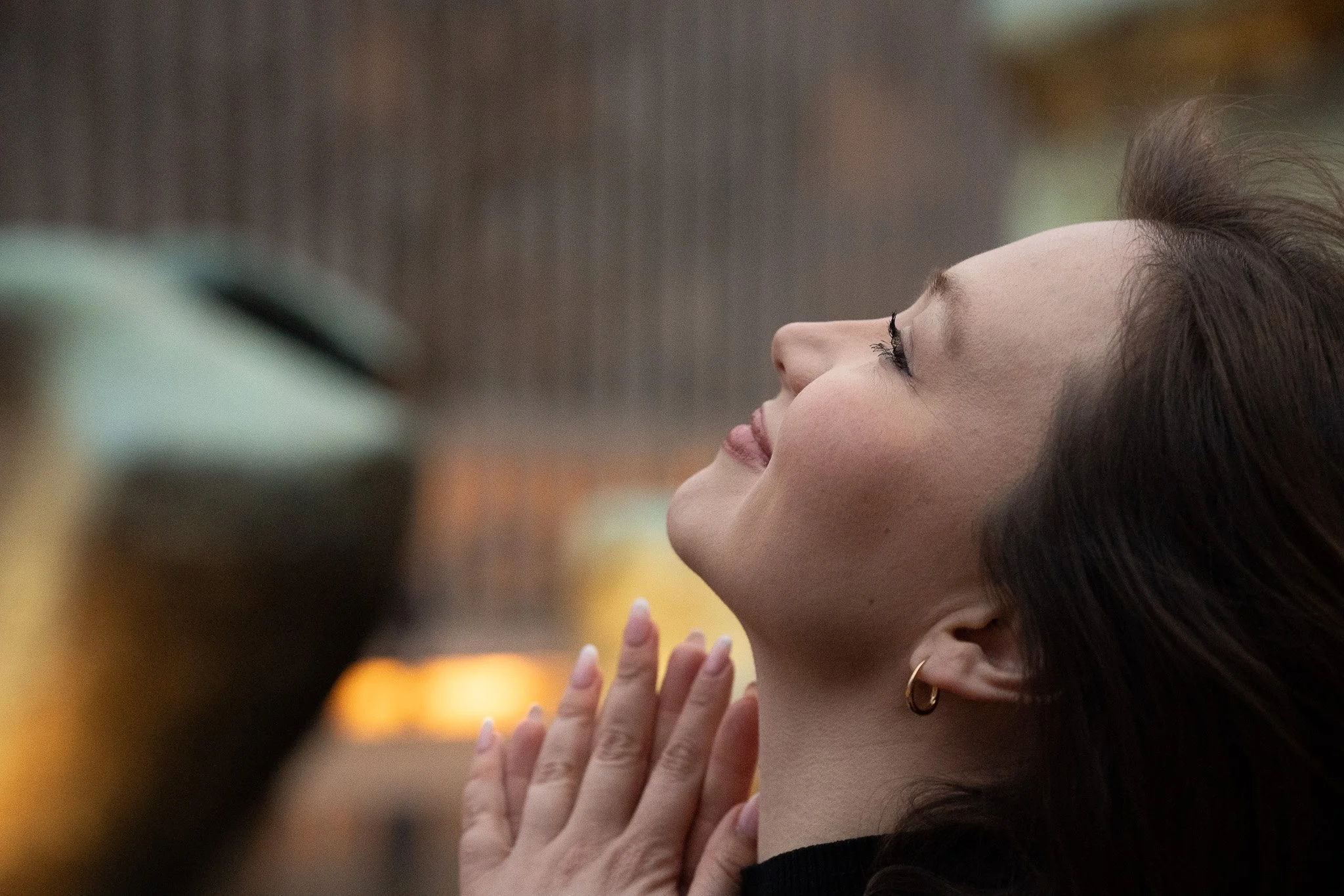 A woman with closed eyes and a peaceful expression holding her hands together near her face in a prayerful pose.