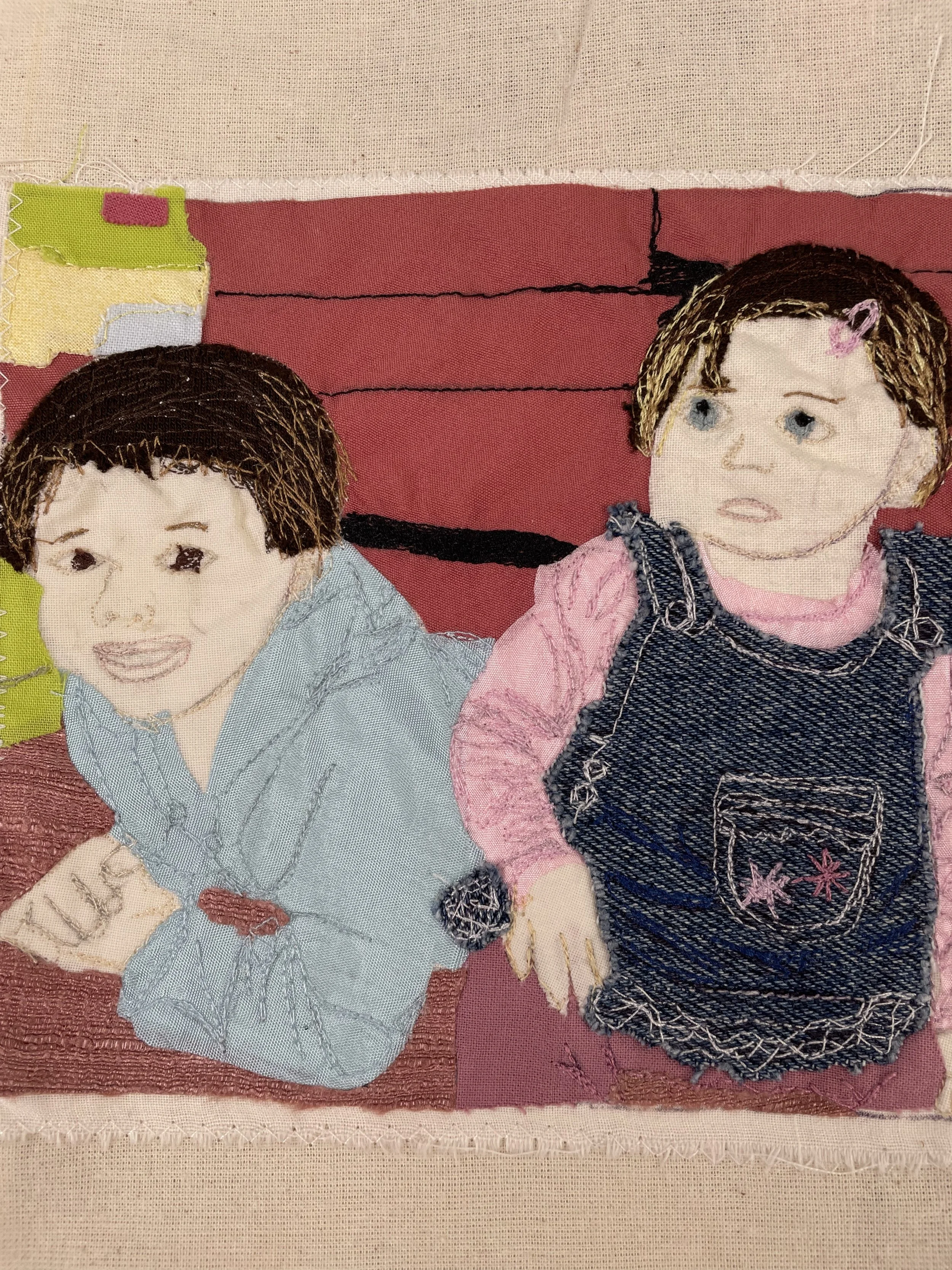 Embroidery artwork of two children, one with short brown hair and the other with longer brown hair, on fabric with a pink and black background.