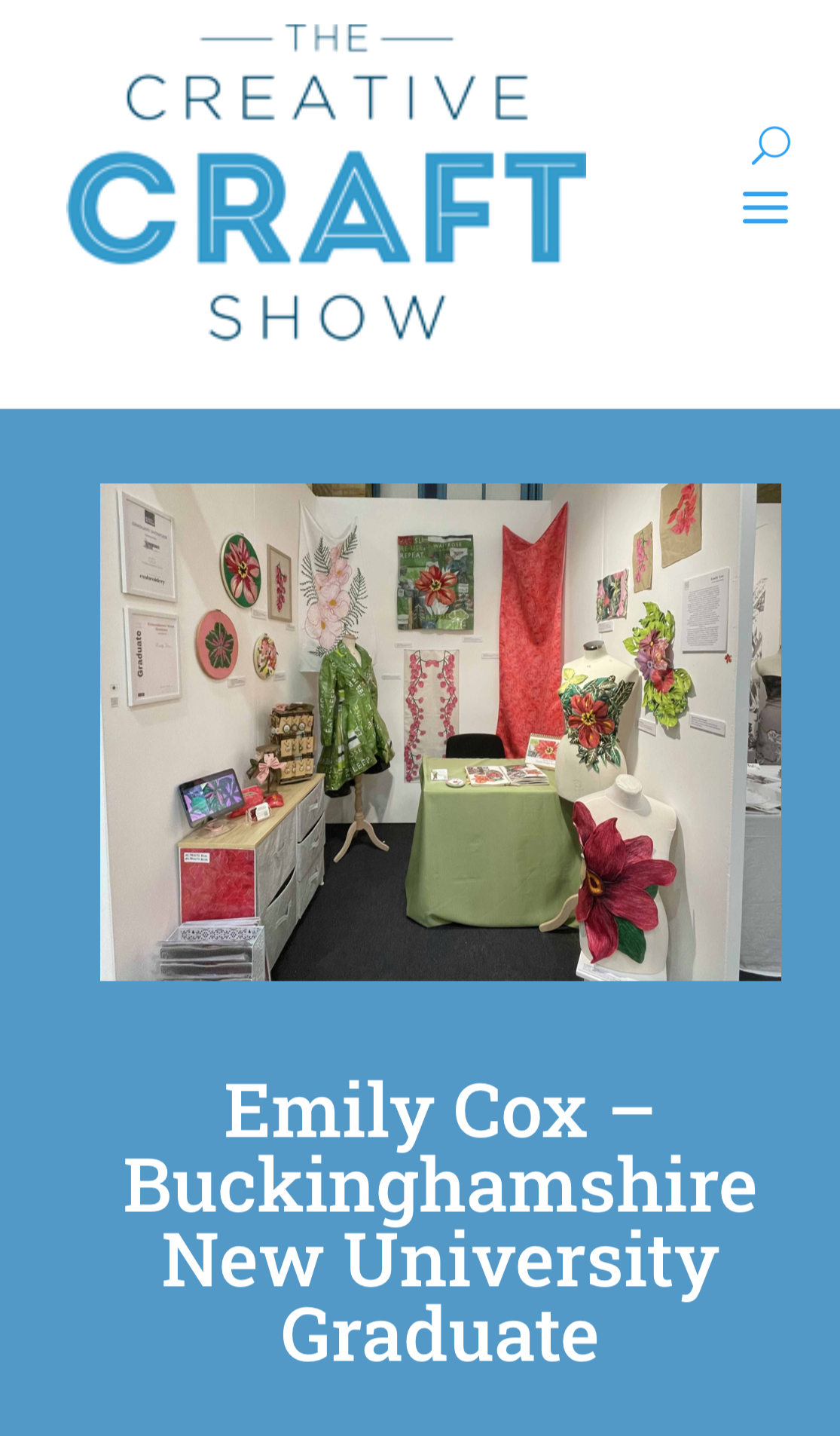 Exhibition booth displaying textile art and craft pieces, including wall hangings, floral artwork, mannequin dressed in green, and a table with brochures, with a sign indicating Emily Cox from Buckinghamshire New University graduate.
