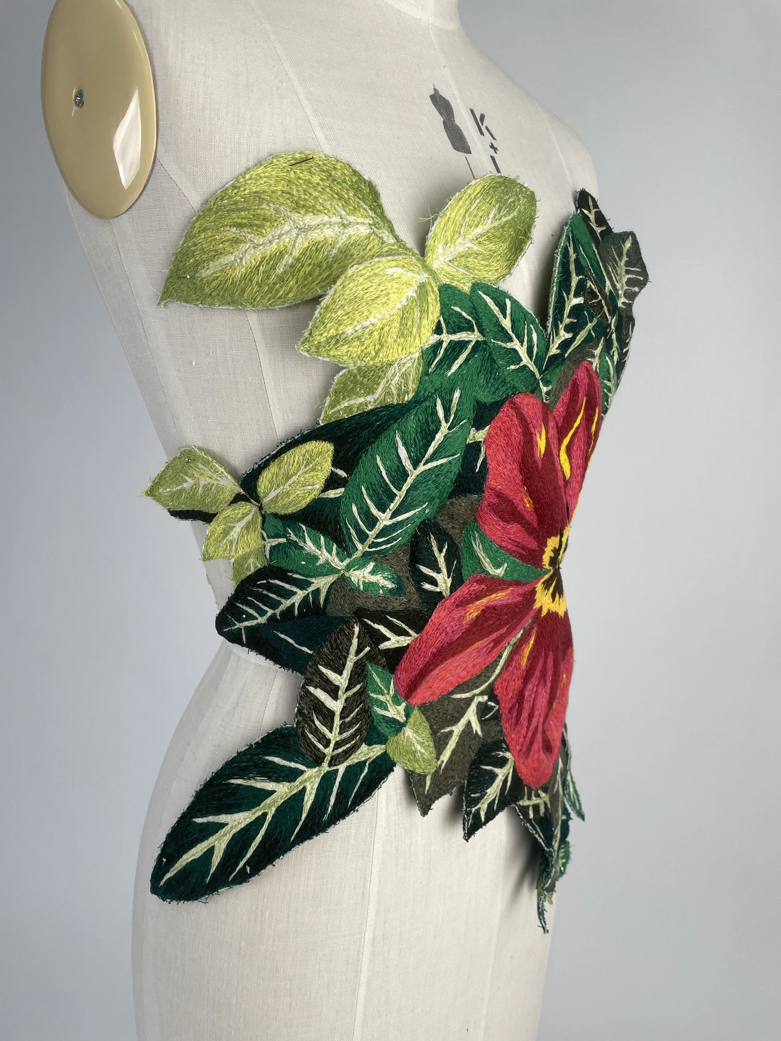 Embroidery of colorful flowers and green leaves on a fabric.