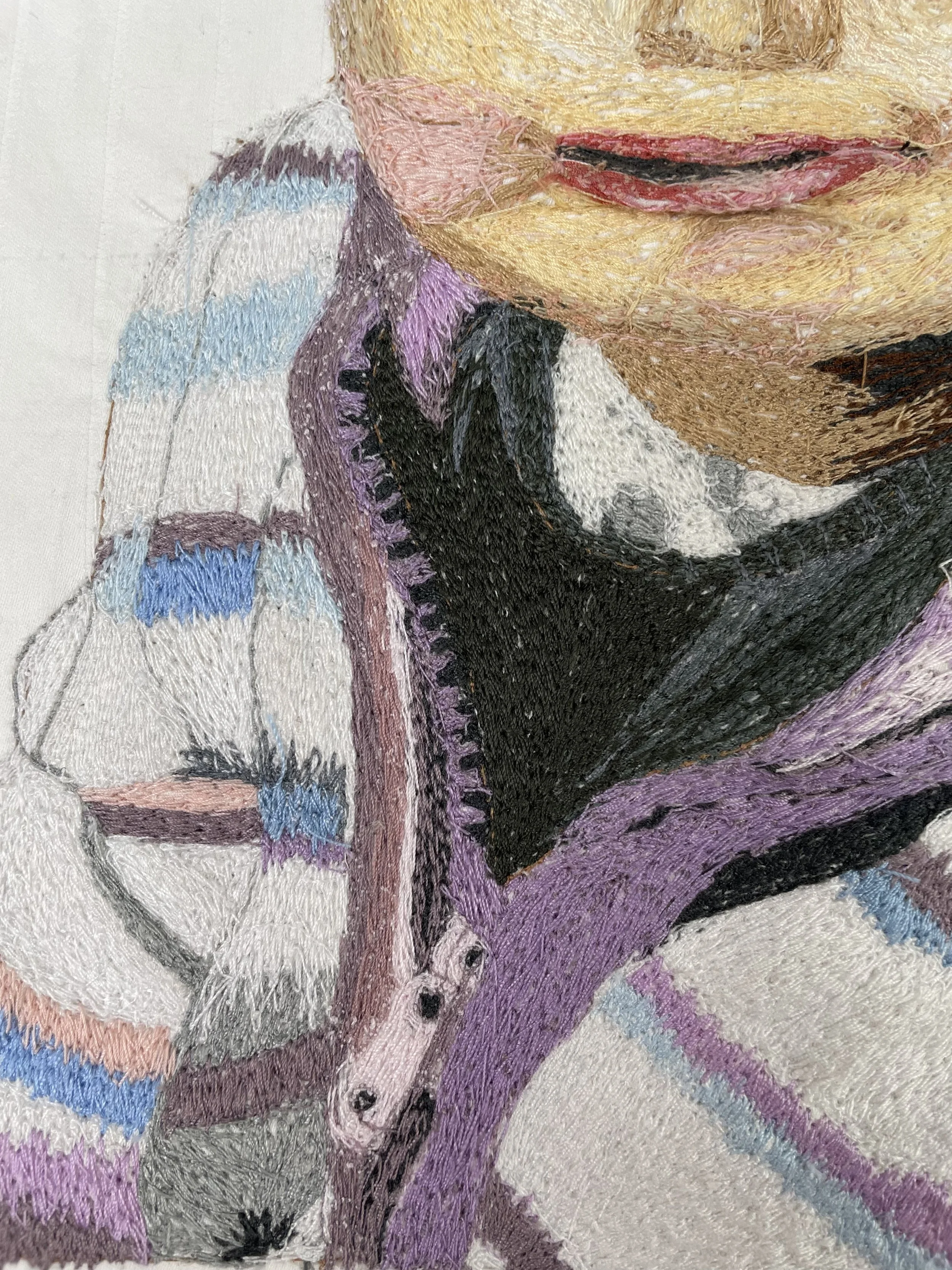 Close-up of a colorful embroidered portrait of a woman with blonde hair, red lips, and purple clothing.