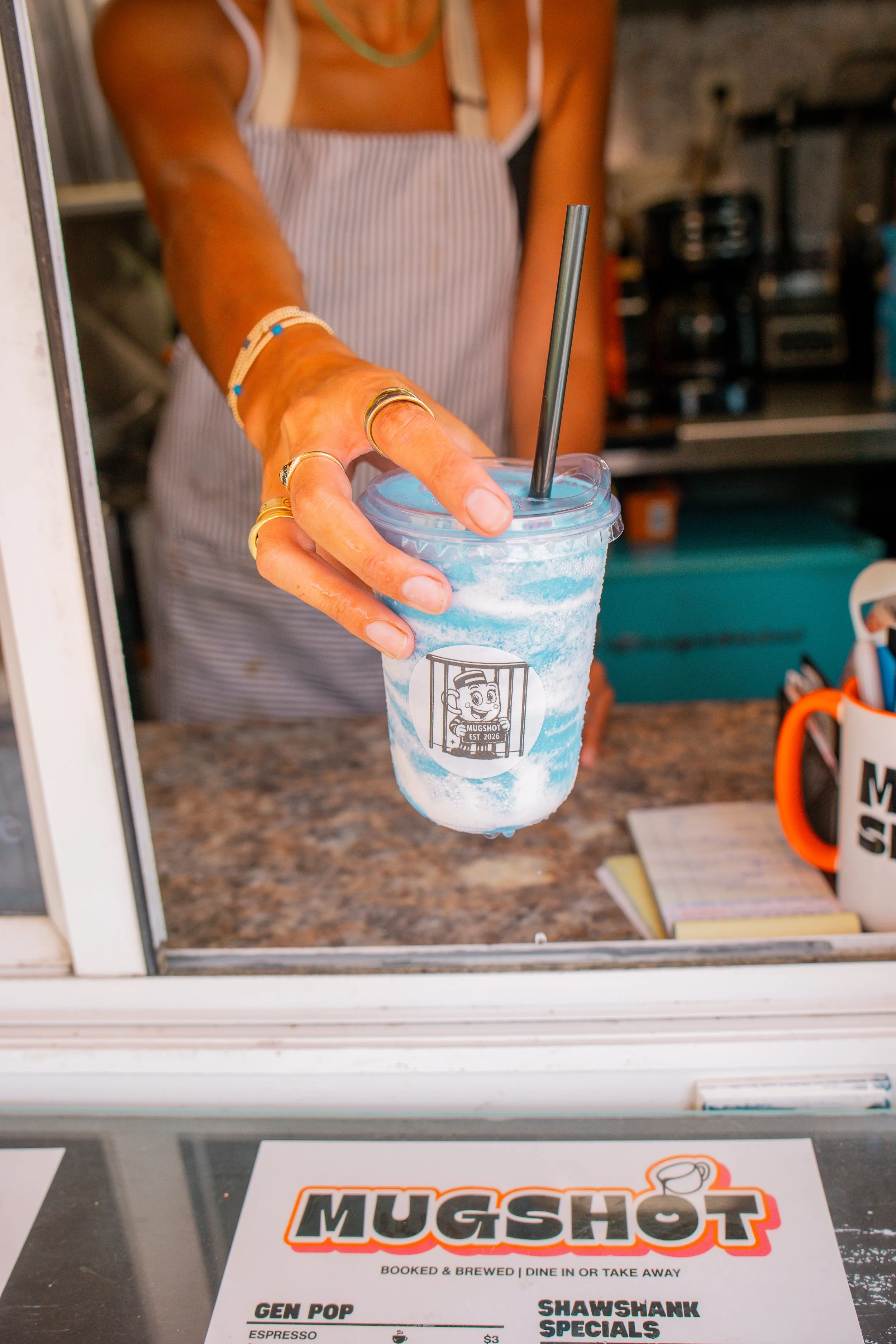 Barista handing blue smoothie to customer at Mugshot Coffee Co