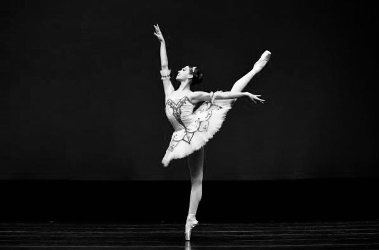 Ballet dancer in tutu performing an arabesque on stage