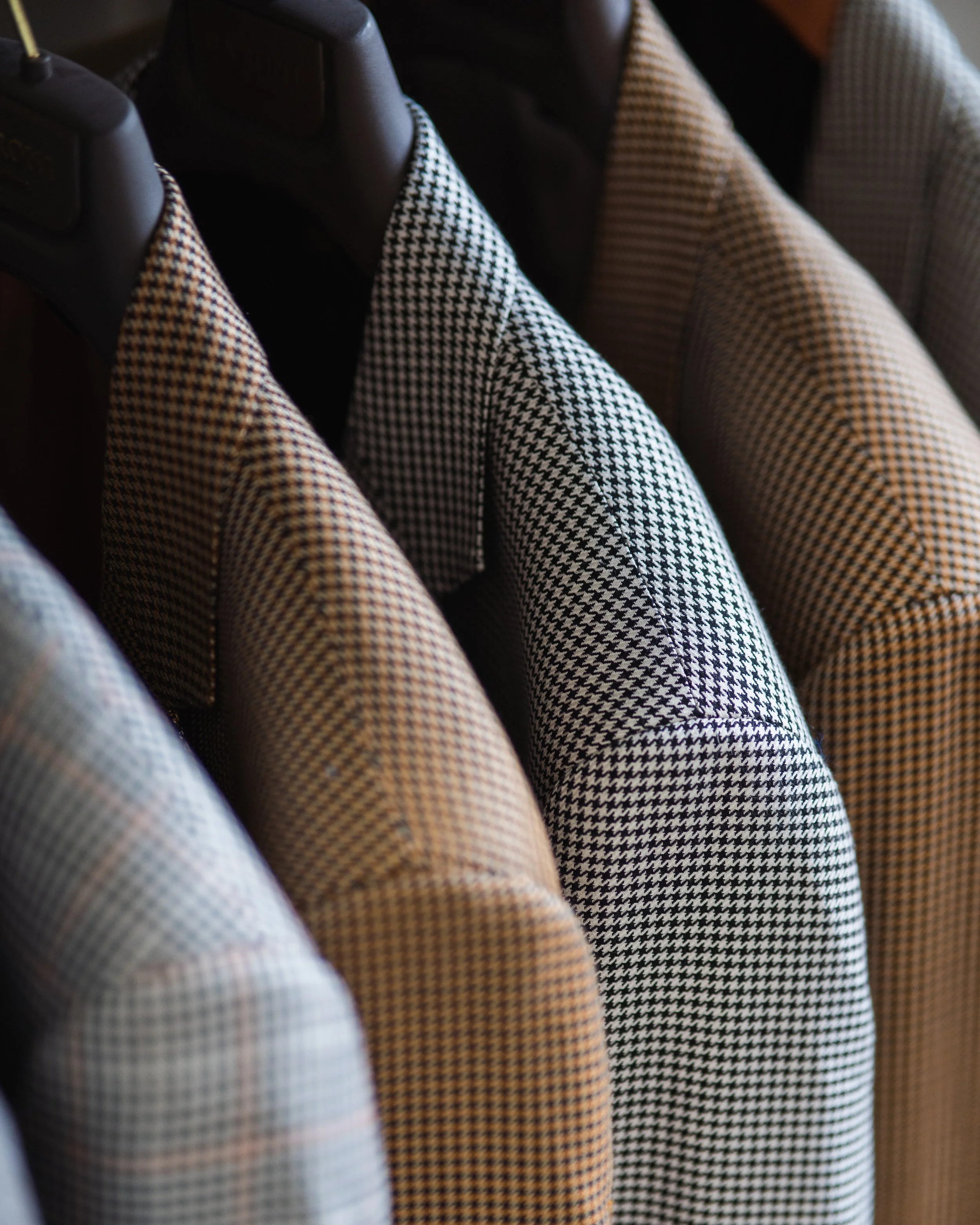 Hanging patterned blazer jackets in various colors on black hangers.