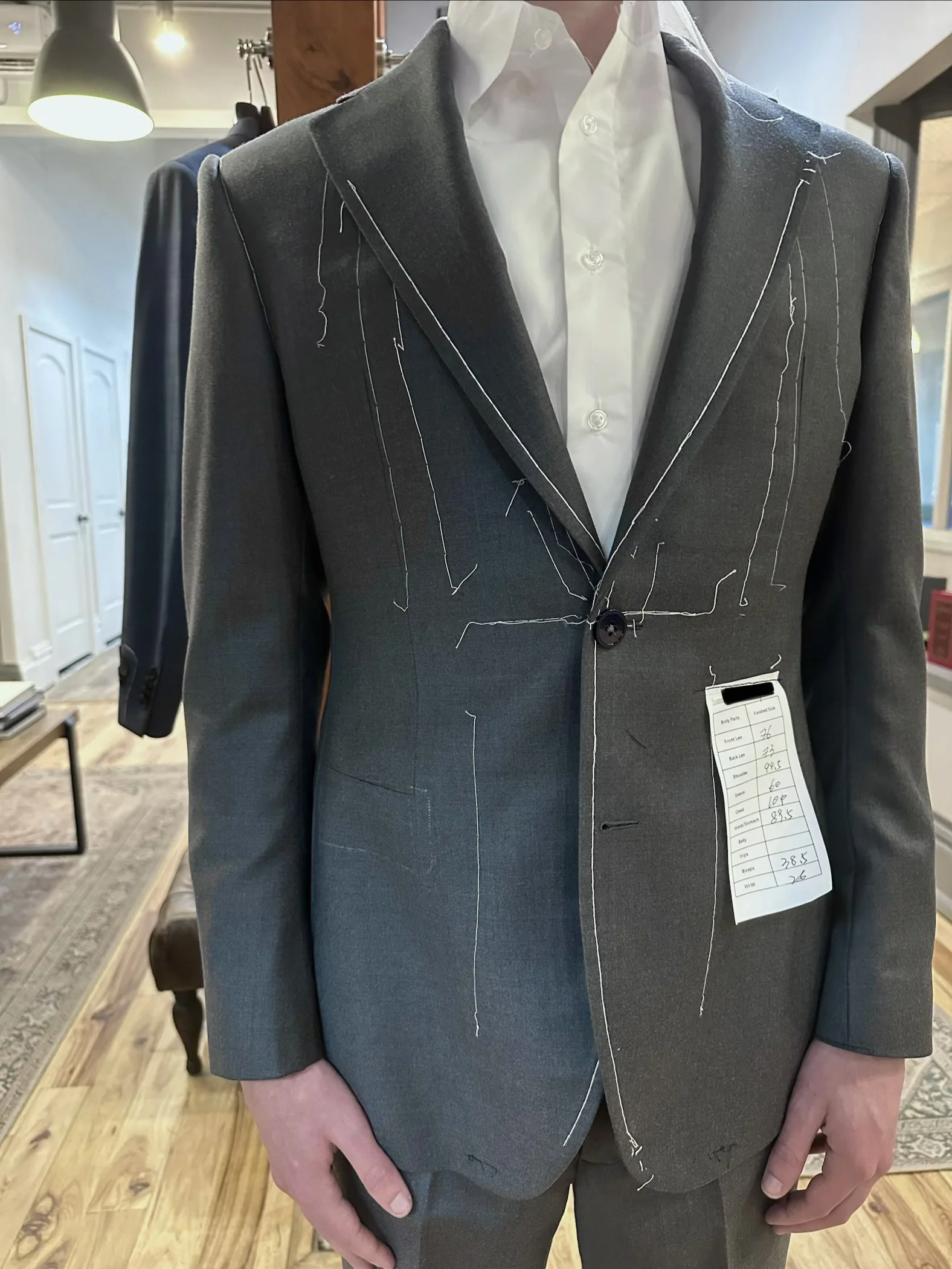 A person trying on a bespoke fitting for a custom suit. The person is also dressed in a white shirt.