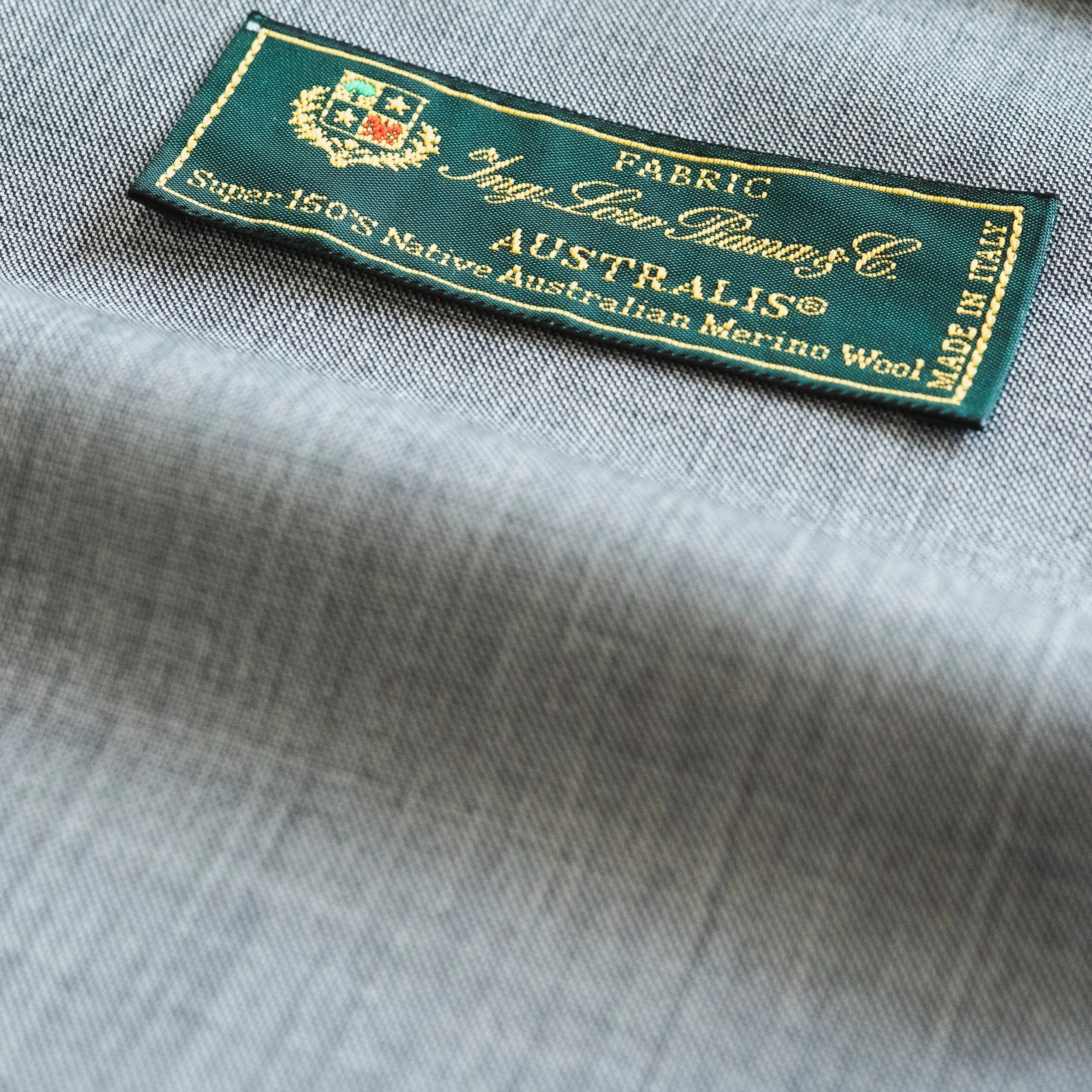 Close-up of a clothing label sewn onto gray fabric.