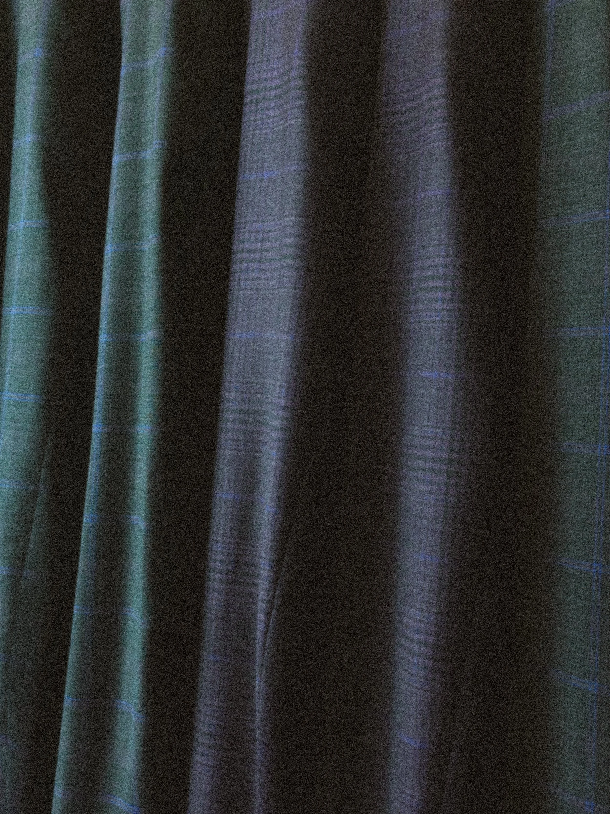 Close up of dark suits with subtle blue and purple colors on a rack.
