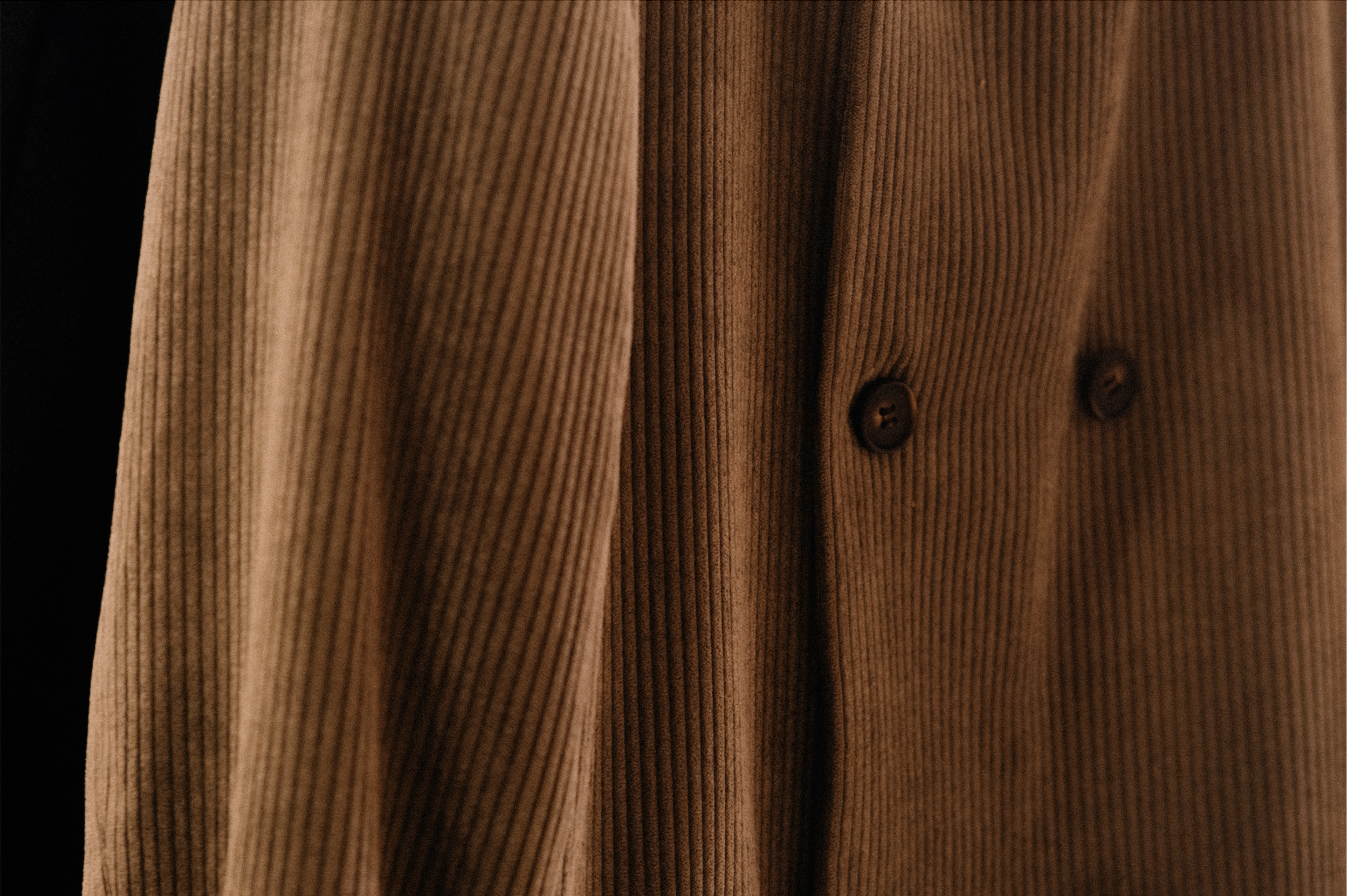 Close-up of a brown corduroy jacket with buttons.