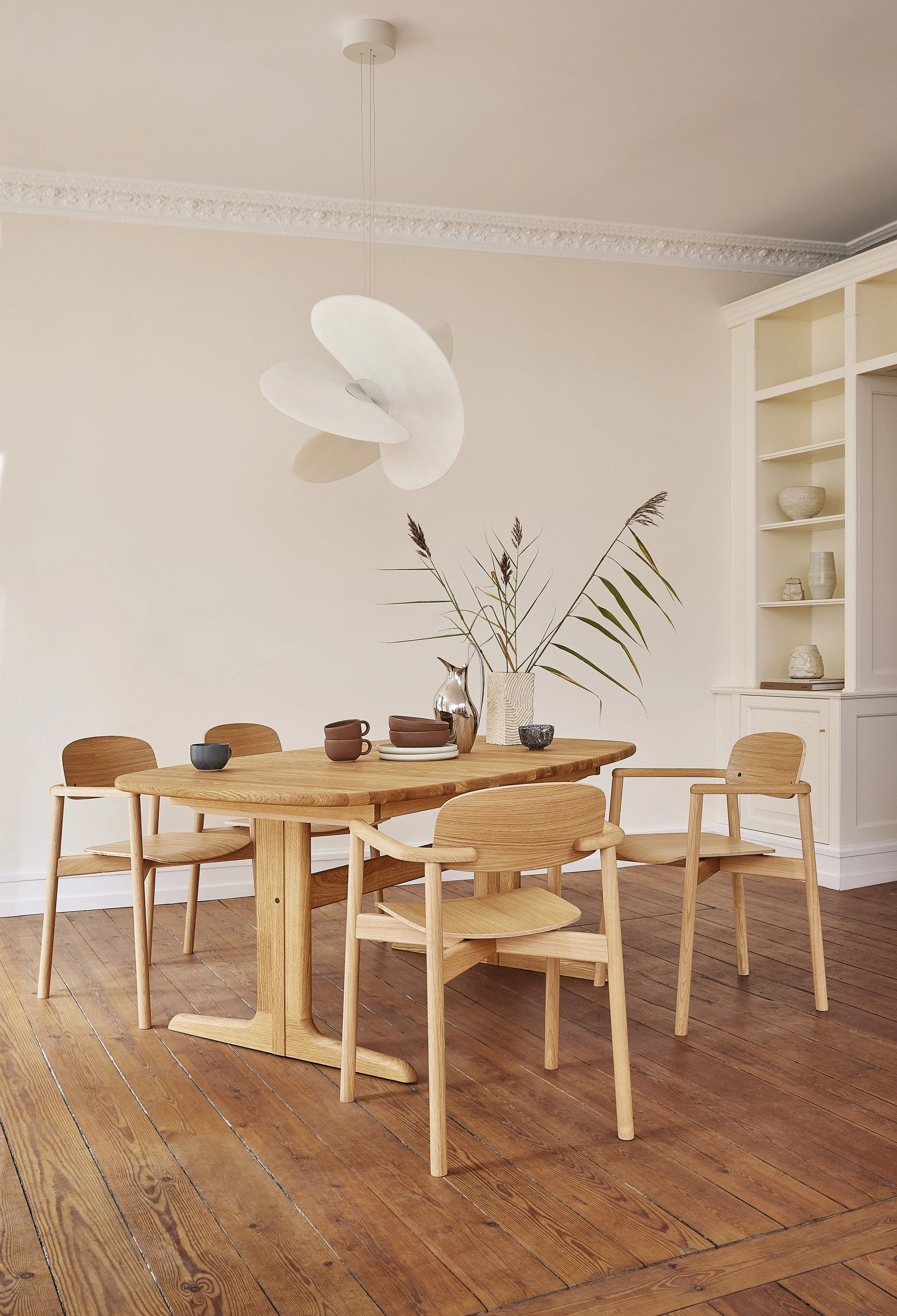 A bright Scandinavian-style dining room with a wooden table and four matching wooden chairs in oak by Skovby