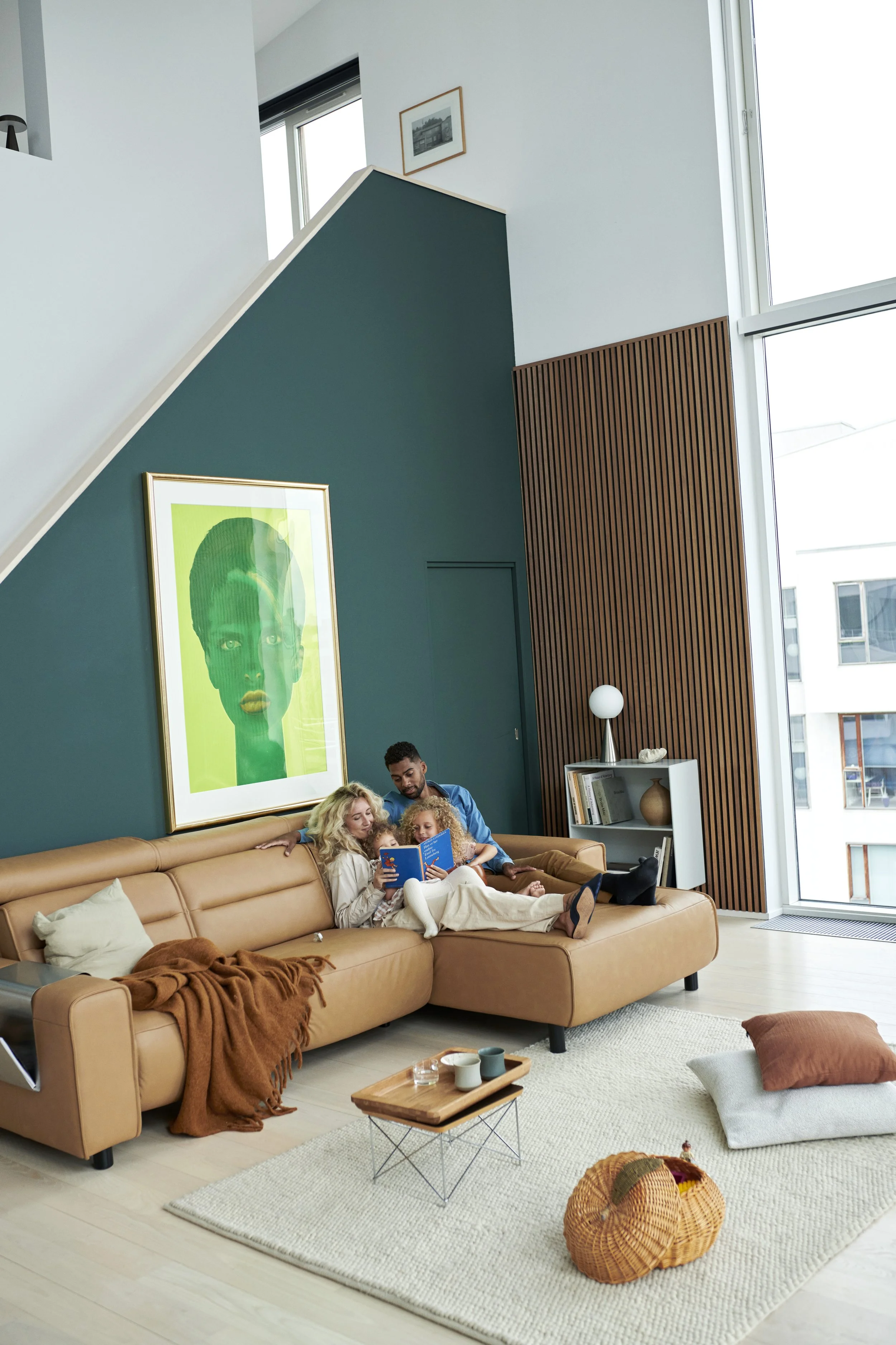 A family of four cuddle together on a tan leather sectional sofa by Stressless in a modern living room