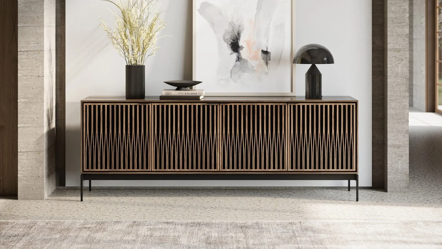 Contemporary wooden sideboard with vertical slats, decorated with black vases, a stack of books, and modern black lamps, against a white wall with abstract art
