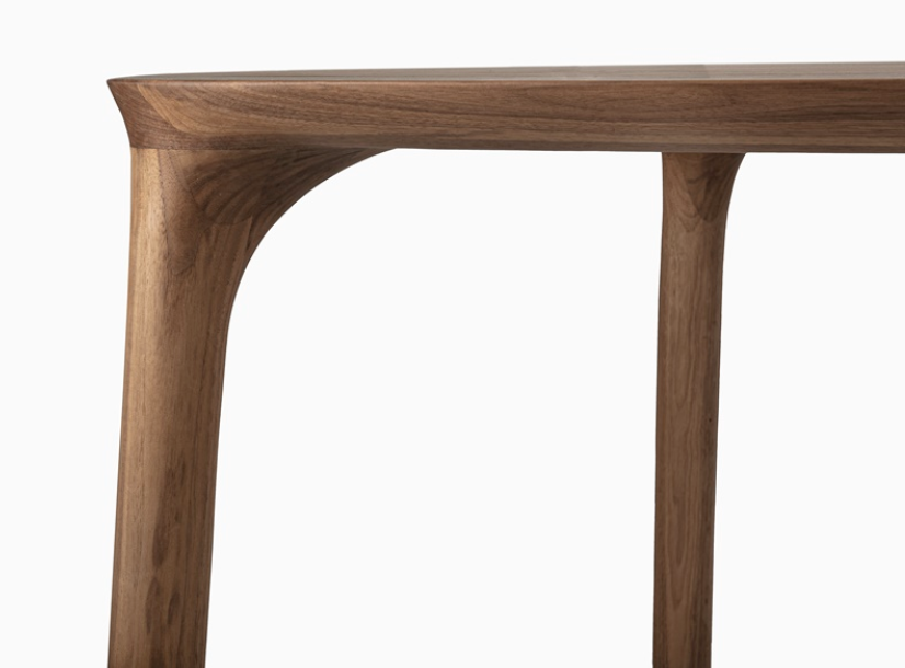Close-up of a wooden table leg and corner on a white background.