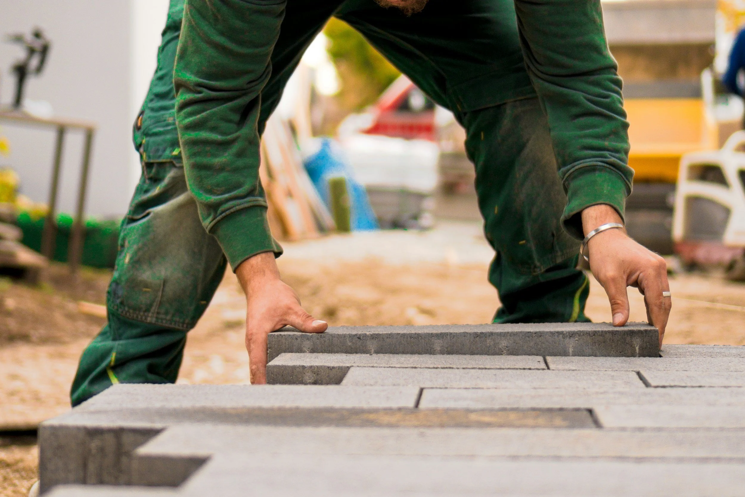 A construction worker installing concrete pavers on a walkway