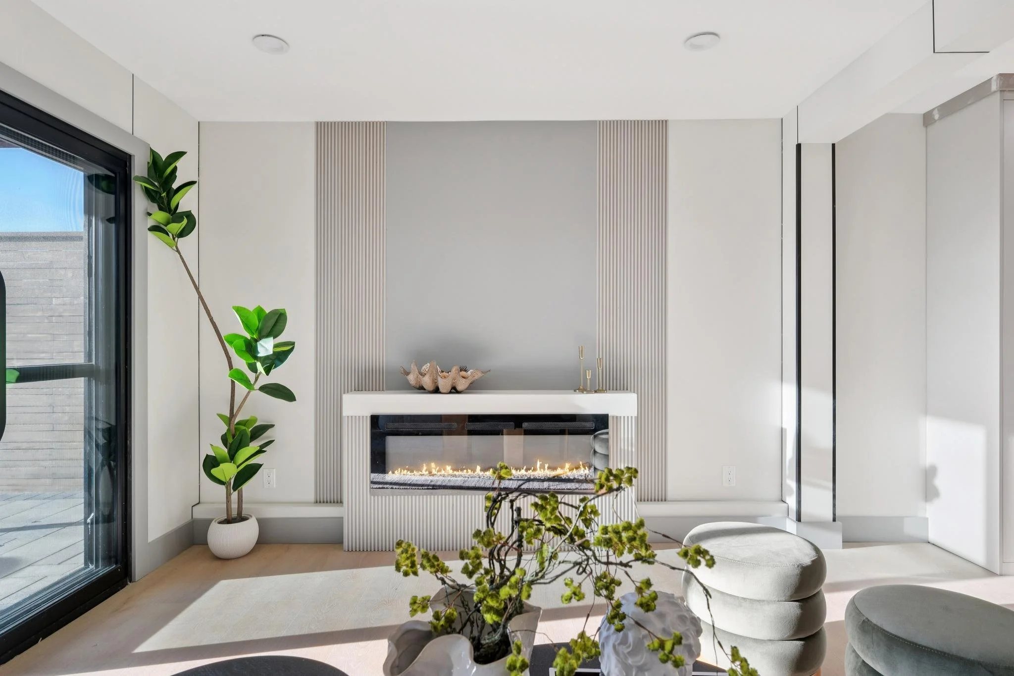 Modern living room with a fireplace, potted plant, and minimalist decor