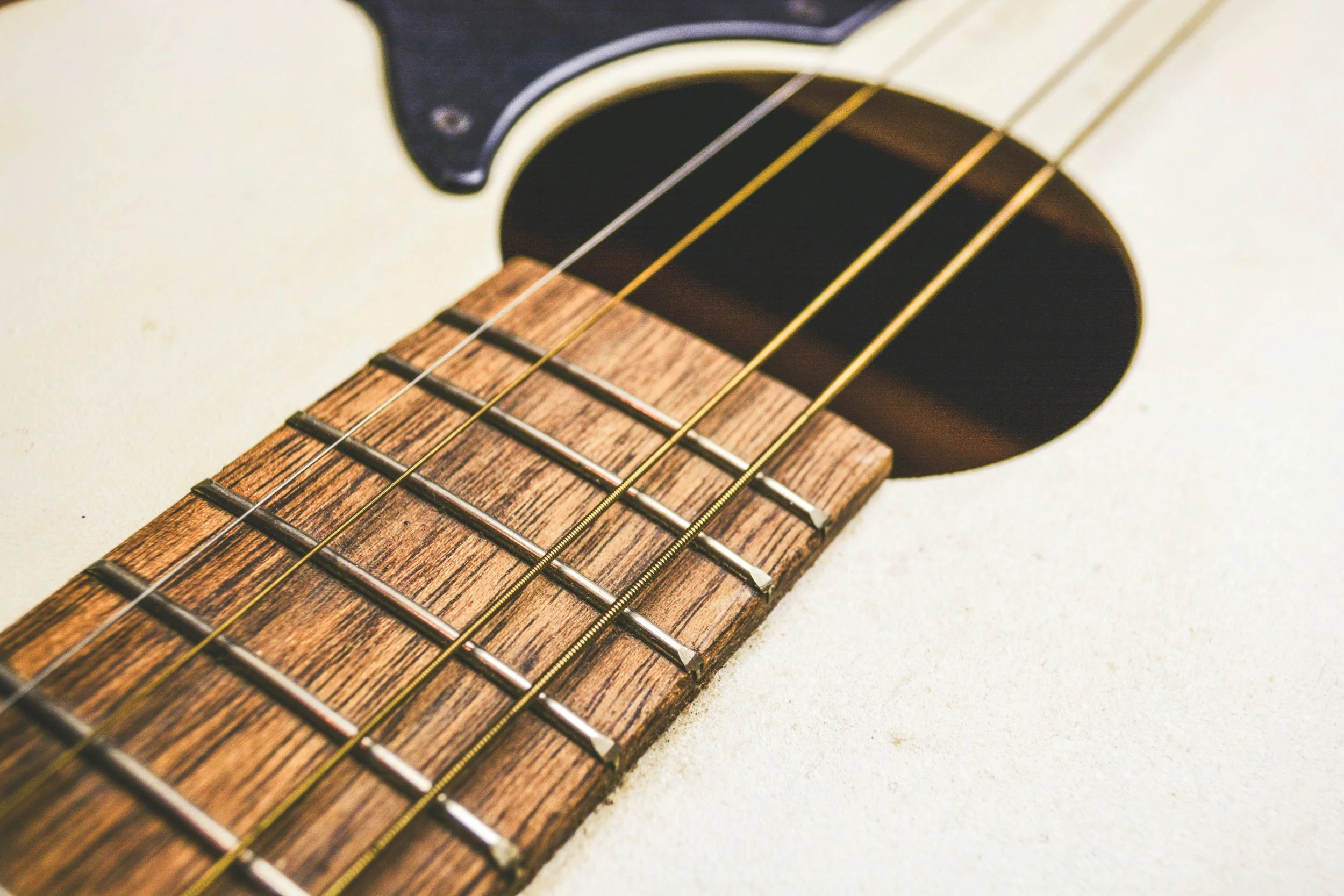 Close-up of an acoustic guitar's neck, strings, frets, and sound hole.