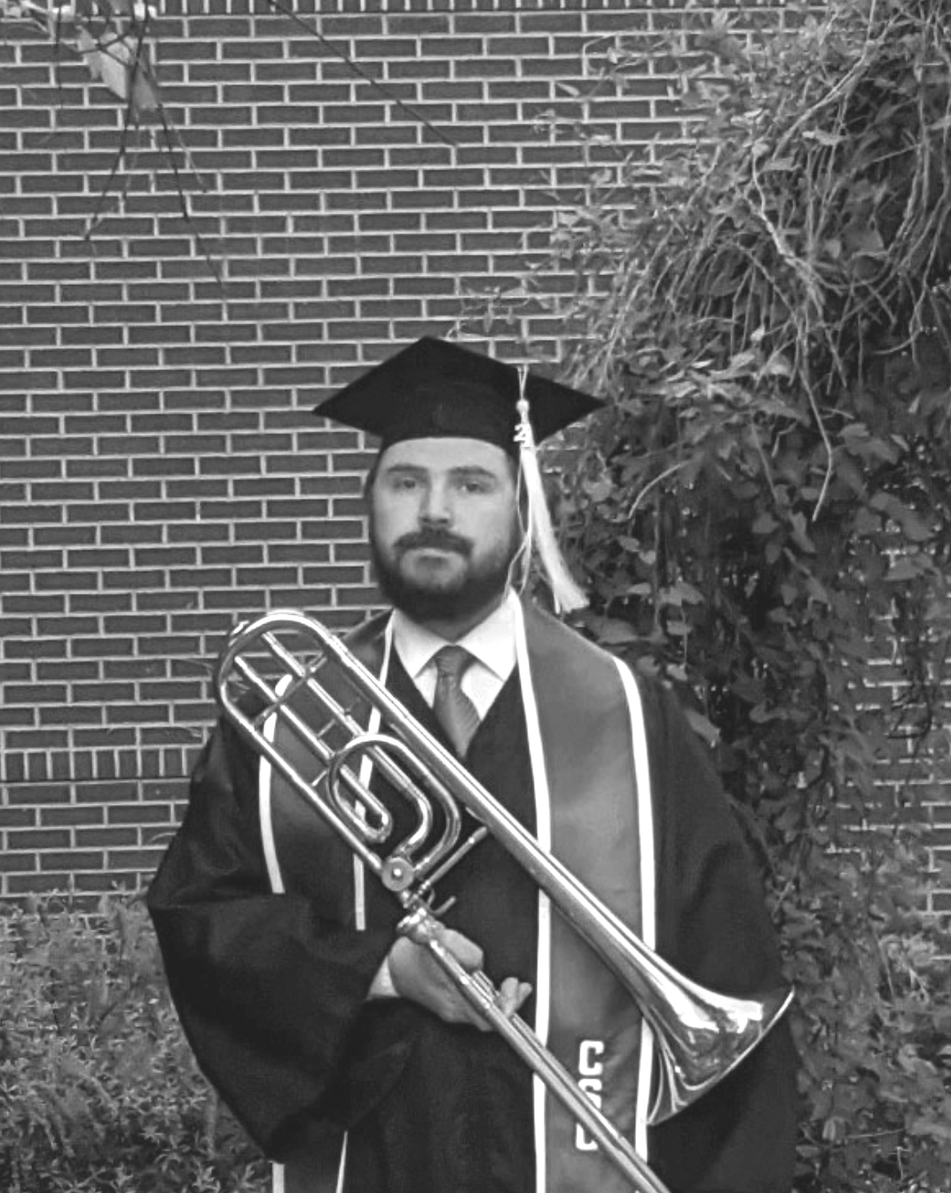 man in cap and gown holding a brass instrument