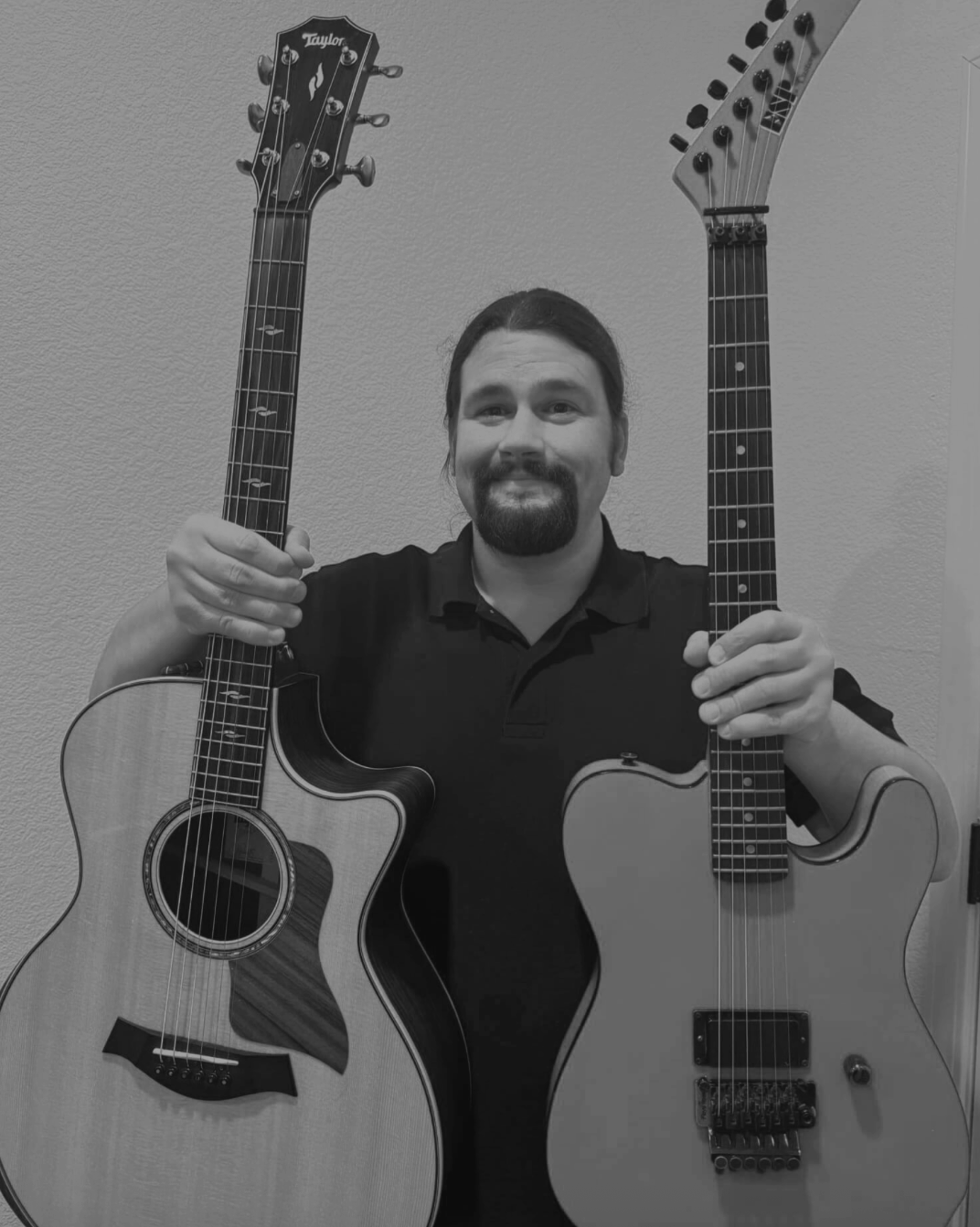 man holding two guitars