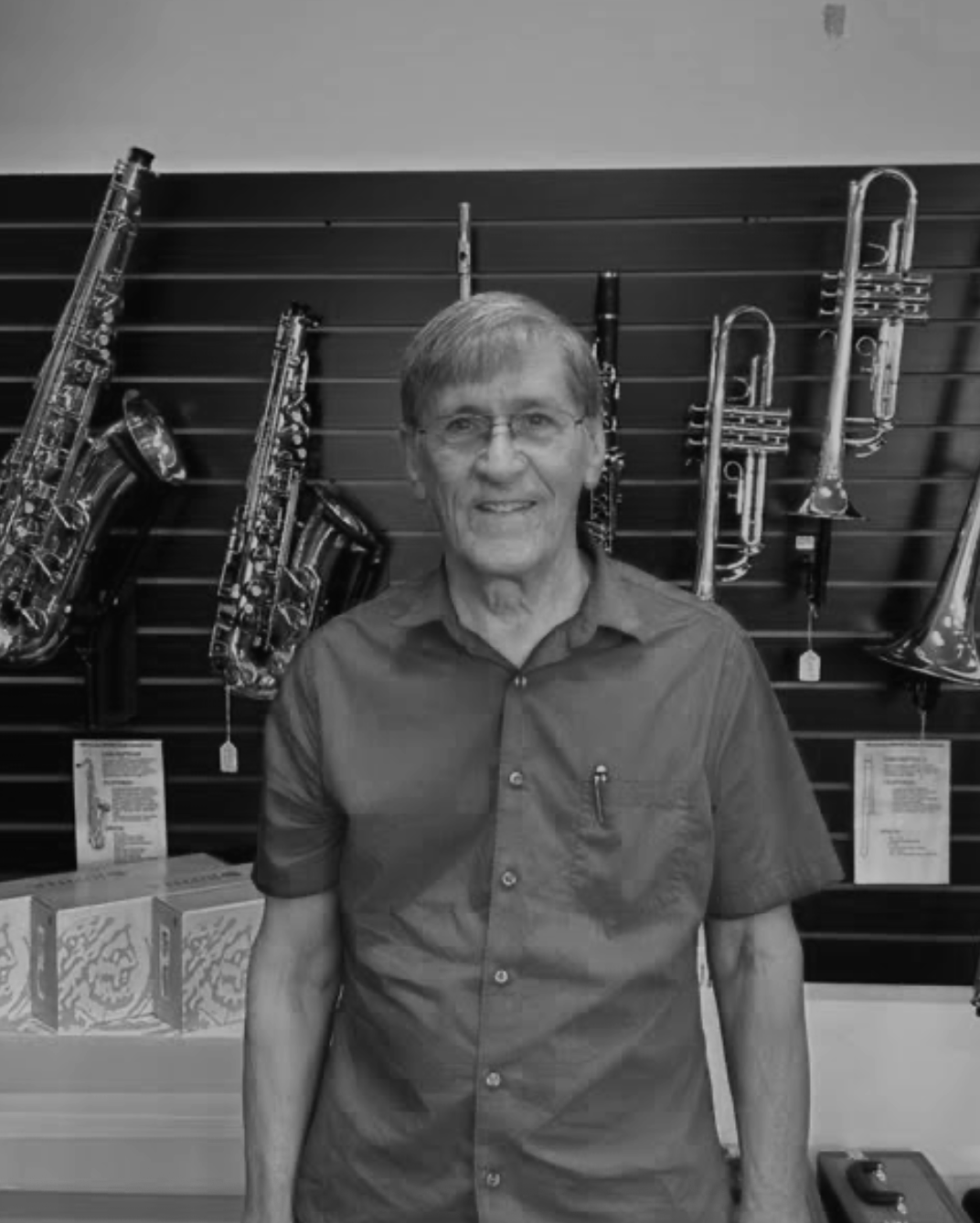 man posing in front of a wall of brass instruments