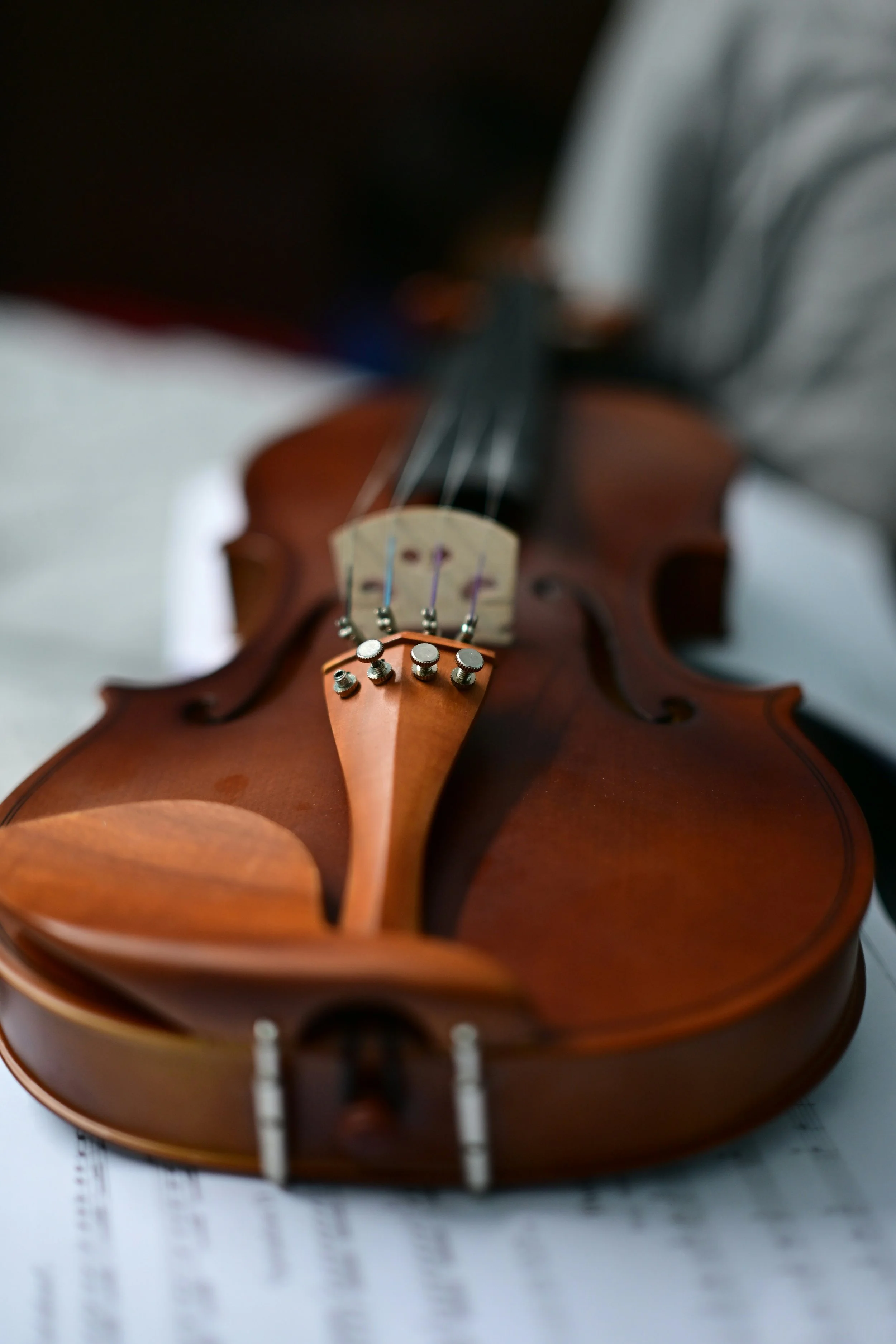Close-up of a wooden violin lying on a sheet of music with black and white notes.