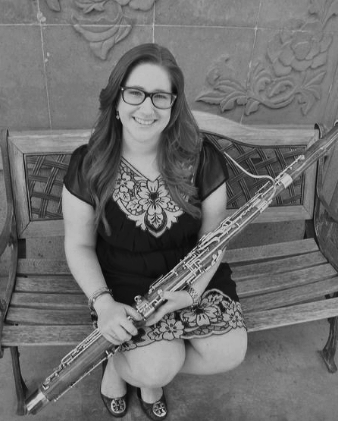 woman sitting on a wooden bench holding a woodwind instrument
