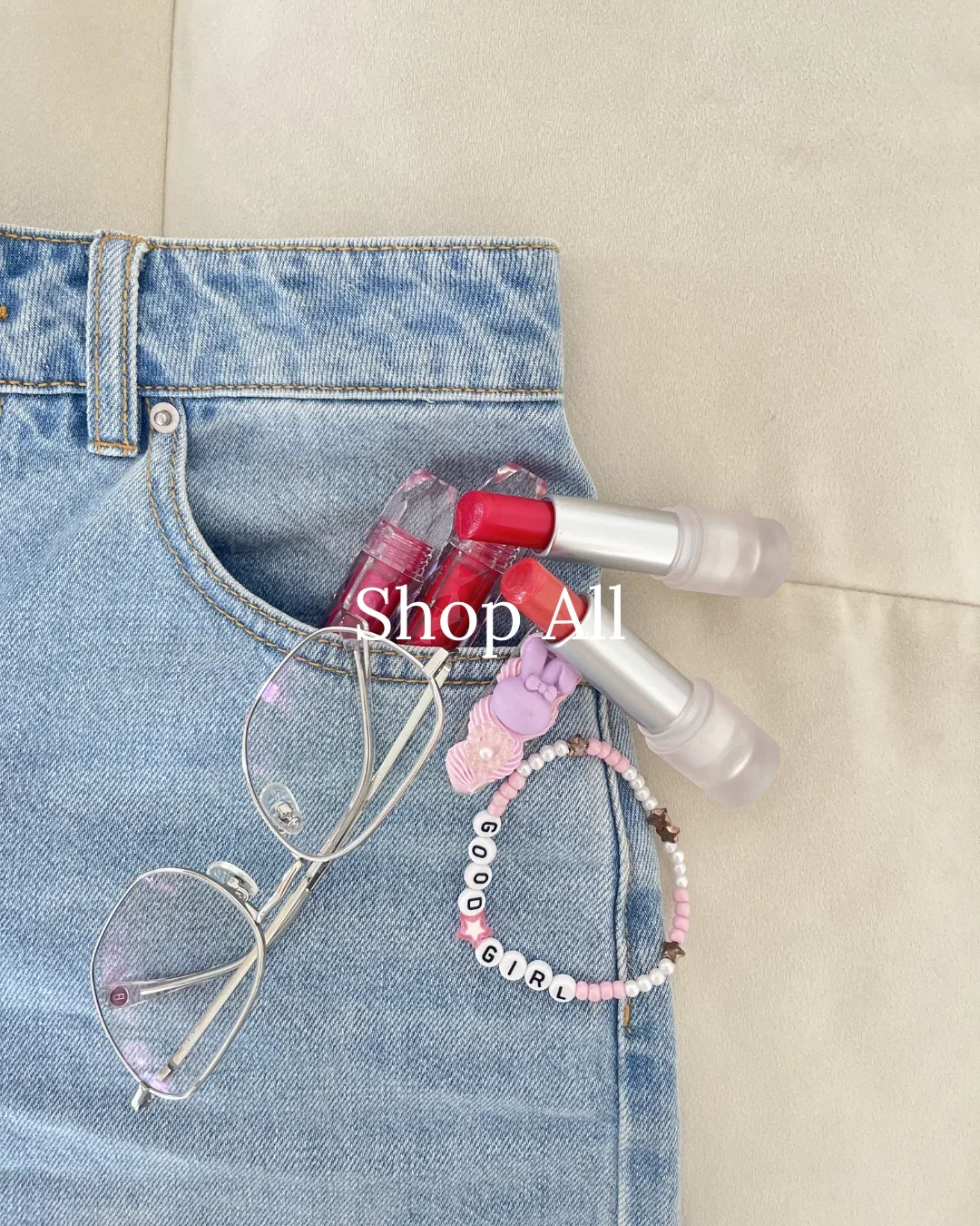 Close-up of denim jeans pocket styled with pink beaded accessories, heart charms, clear-frame glasses, and a lip gloss — Shop All Chulip accessories