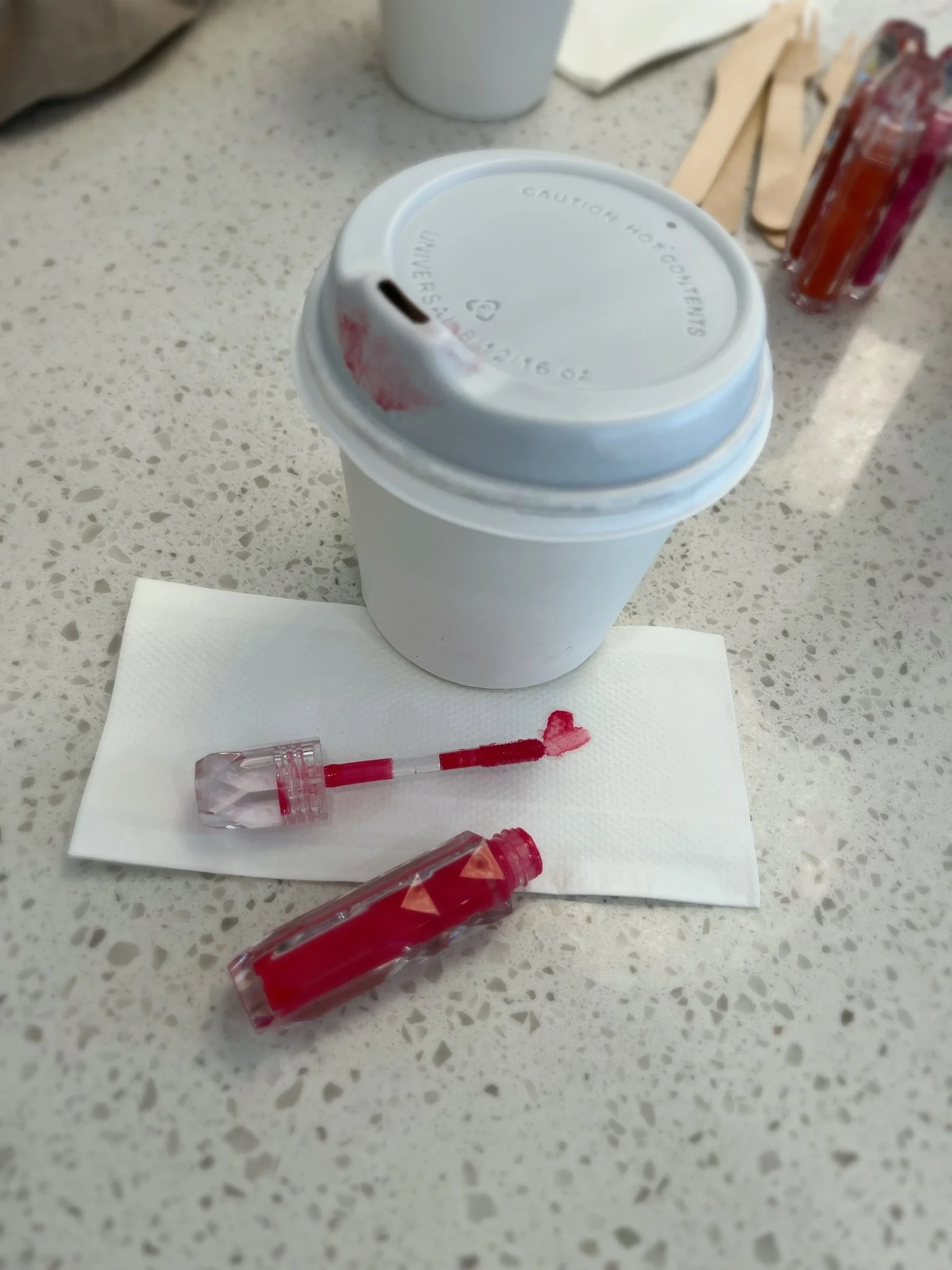 Pink Chulip lip gloss tube placed next to a white takeaway coffee cup on a marble surface — Chulip pure ingredients minimalist lifestyle