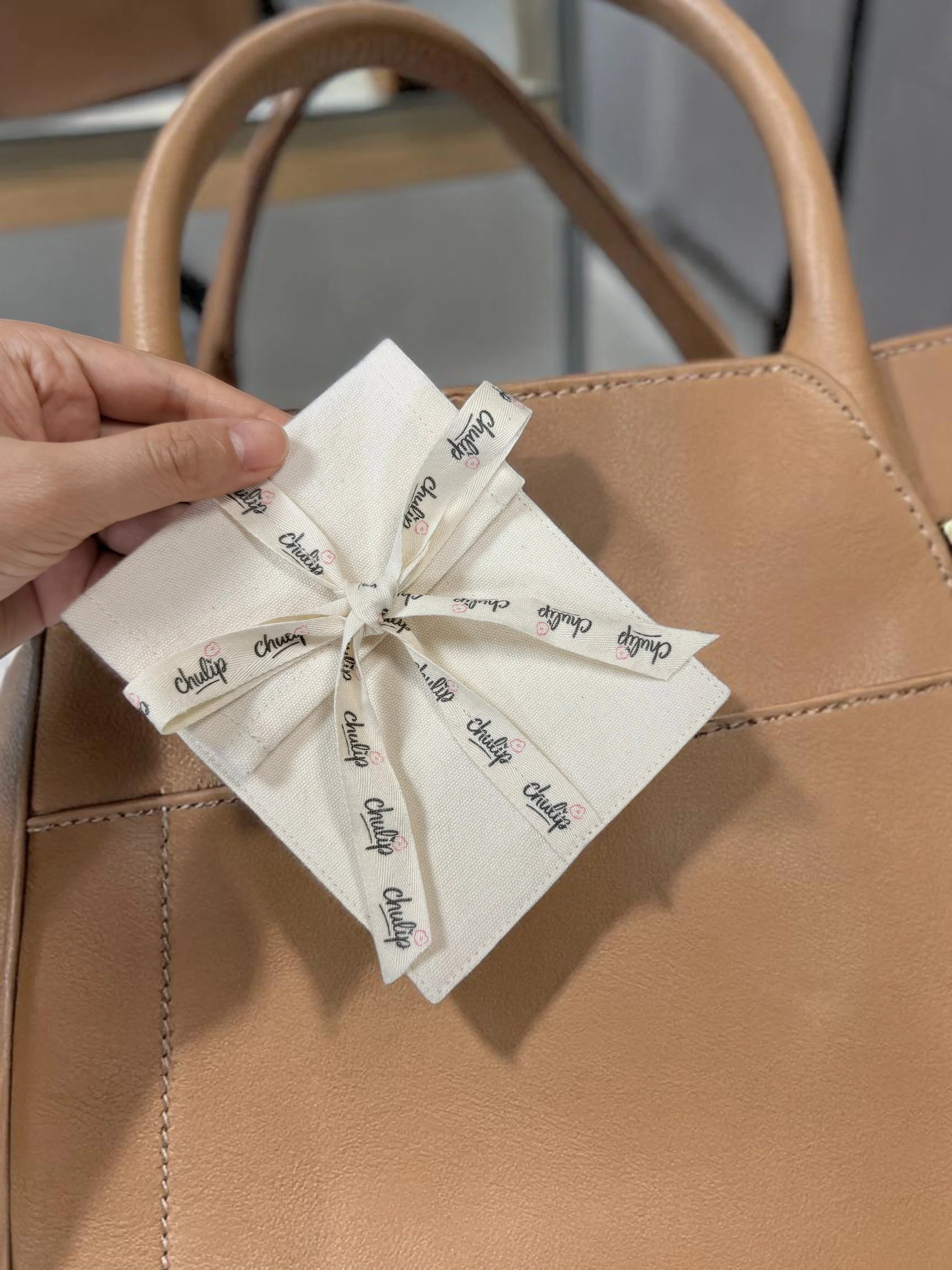 Hands holding a white cotton mini ribbon bag with Chulip's logo on— Chulip packaging goodies in cuties