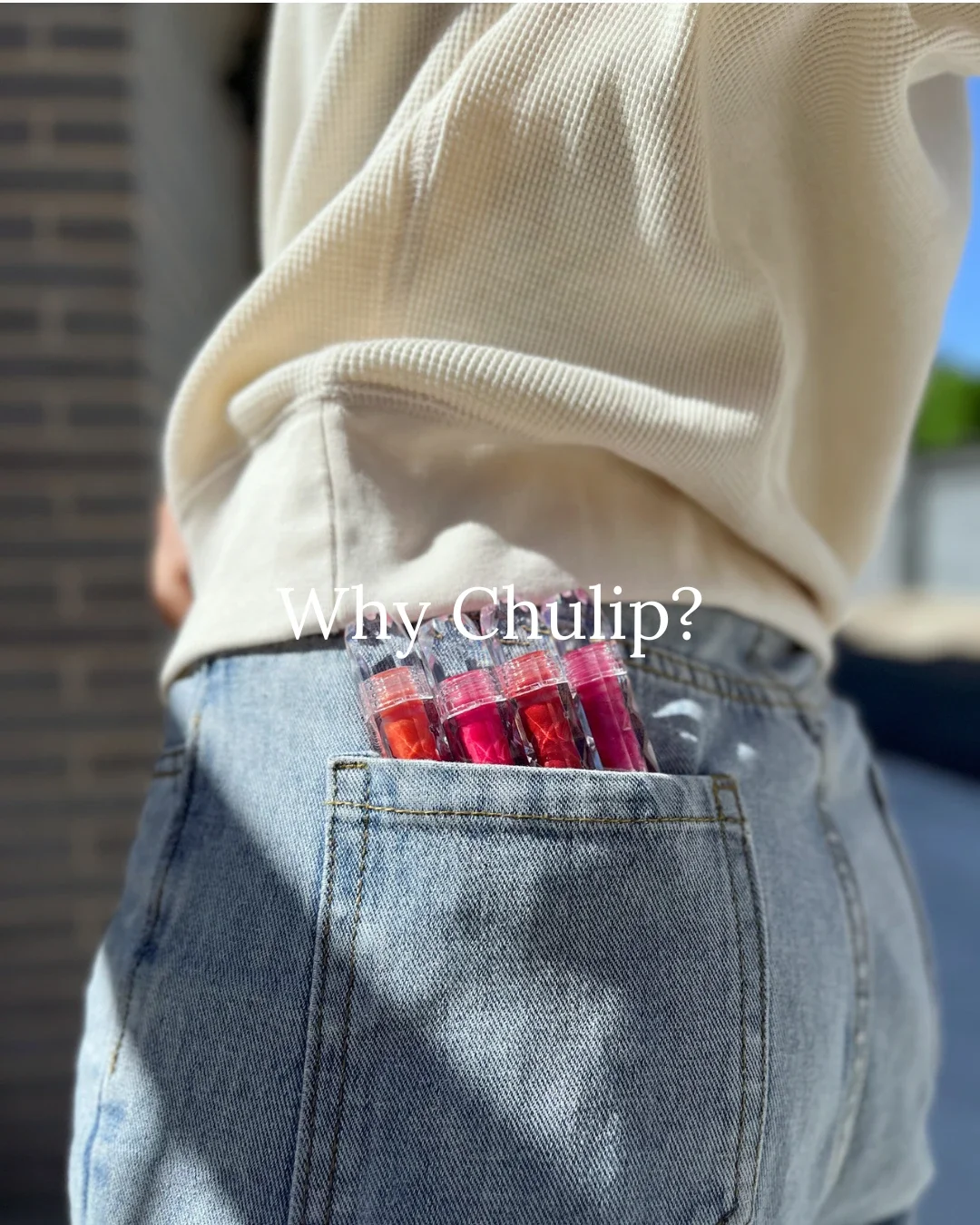 Side view of a person in a beige knit top with denim jeans, pocket filled with red and pink lip glosses — Why Chulip?