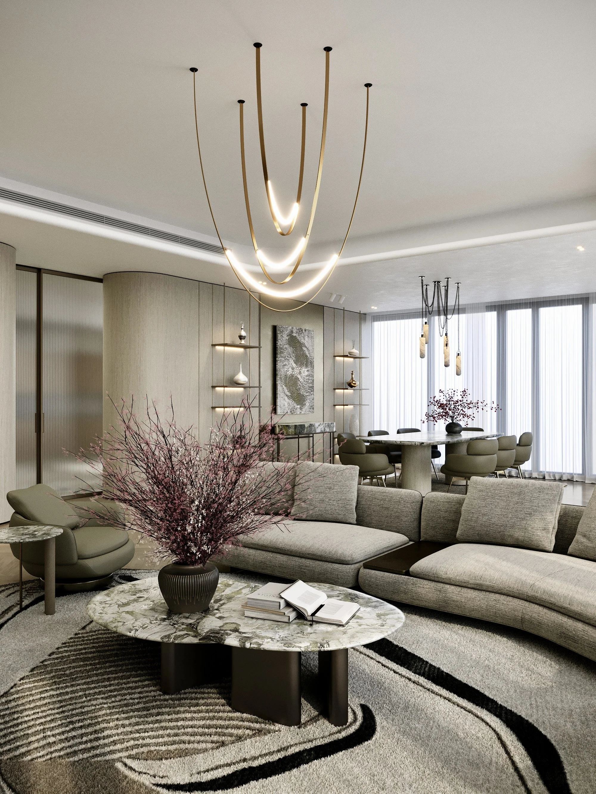 Modern living room with a large gray sectional sofa, a marble coffee table with books, a purple flower arrangement, and contemporary chandelier lighting. The room features a neutral color palette, textured curtains, and wall art.