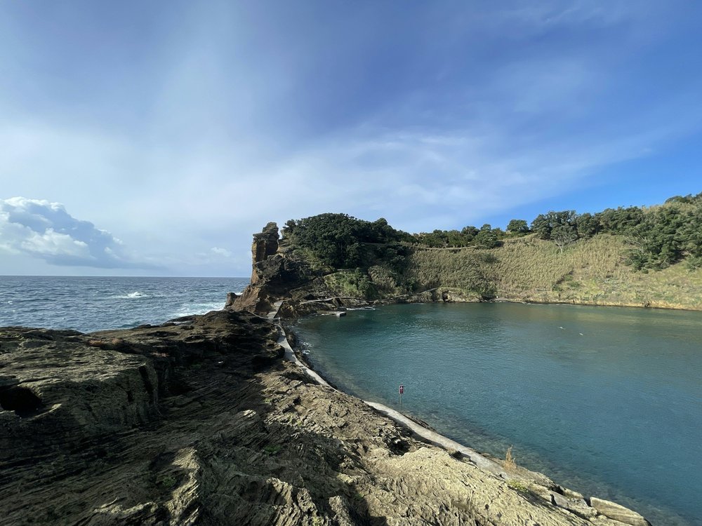 Rocky volcanic coastline with a turquoise natural pool on São Miguel Island, Azores.