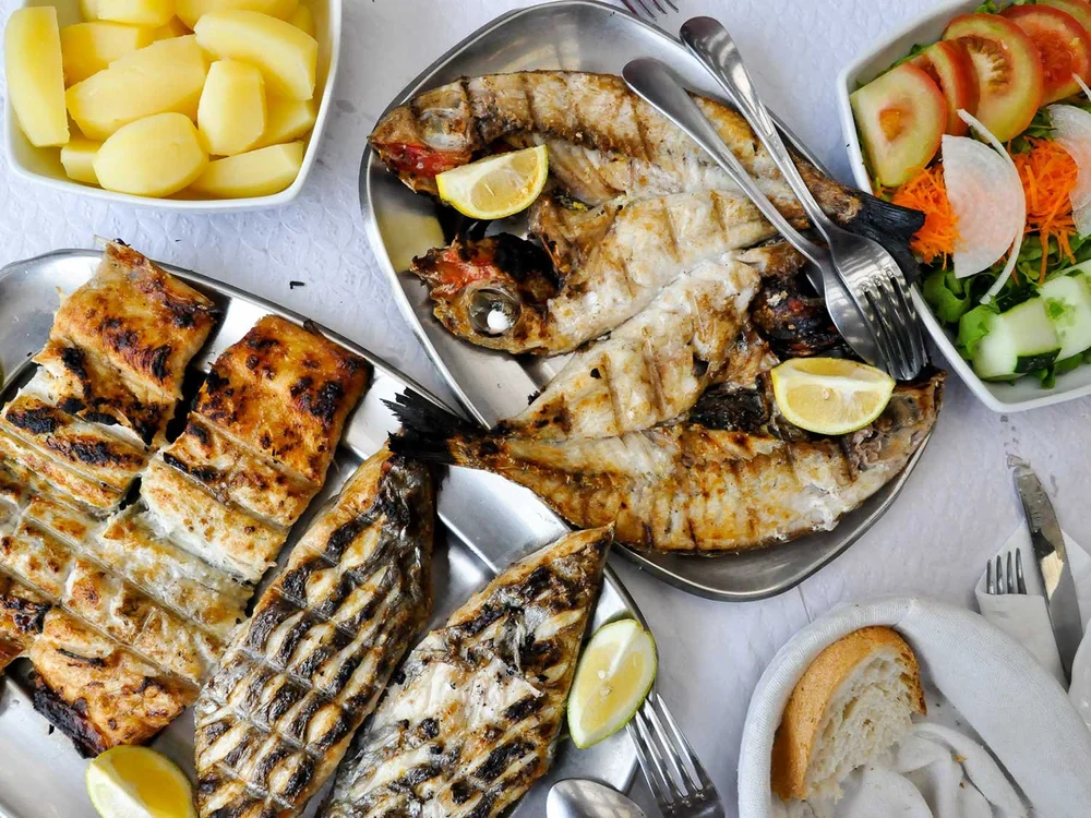 Grilled fish and traditional Azorean food spread on a table at a local restaurant in São Miguel.