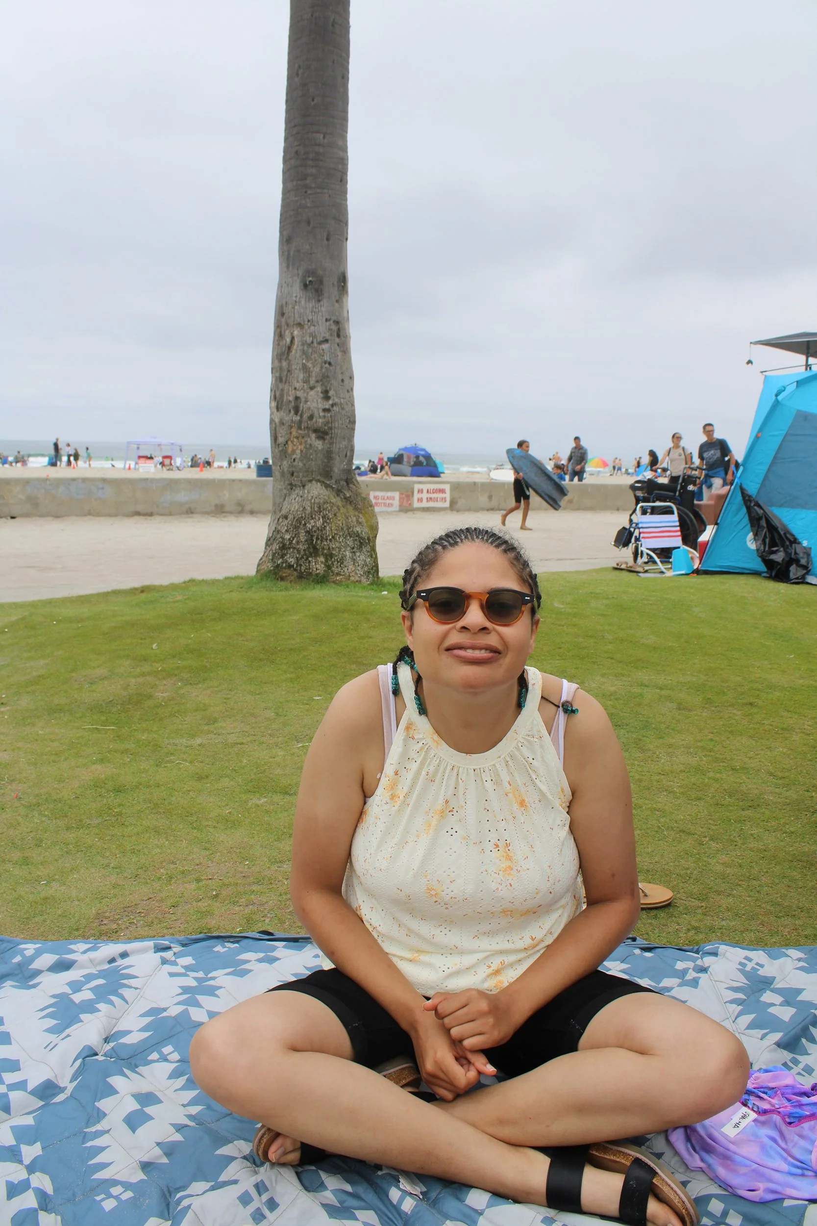 Woman smiles on blanket by the beach
