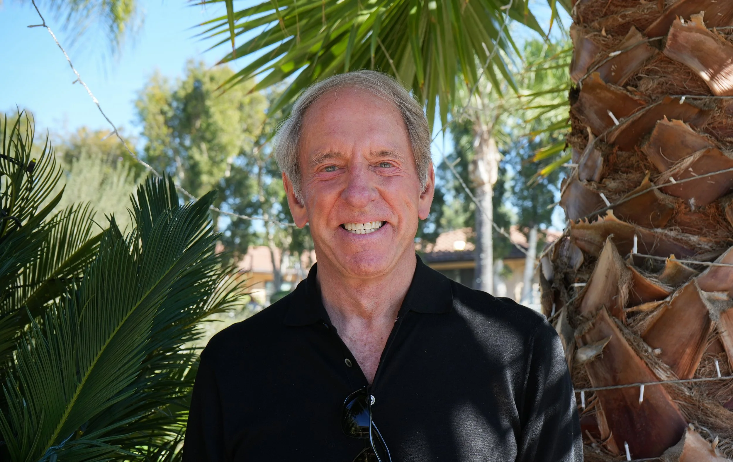 Headshot of man standing by palm trees