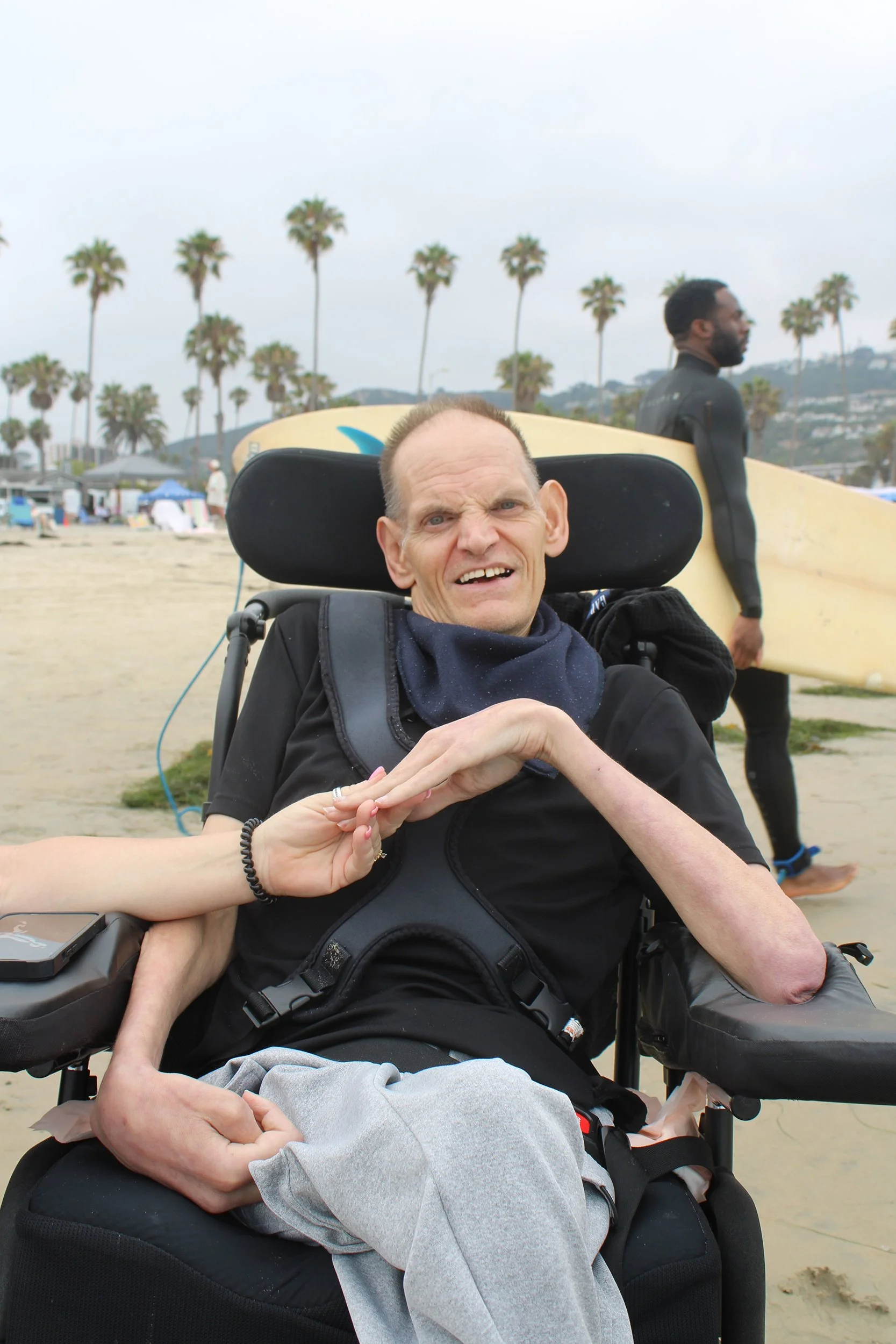 Man in wheelchair smiles on cloudy beach