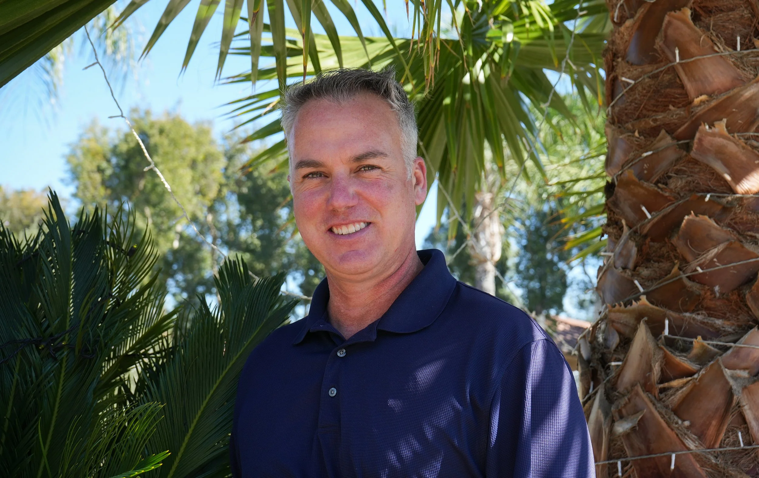 Headshot of man standing by palm trees
