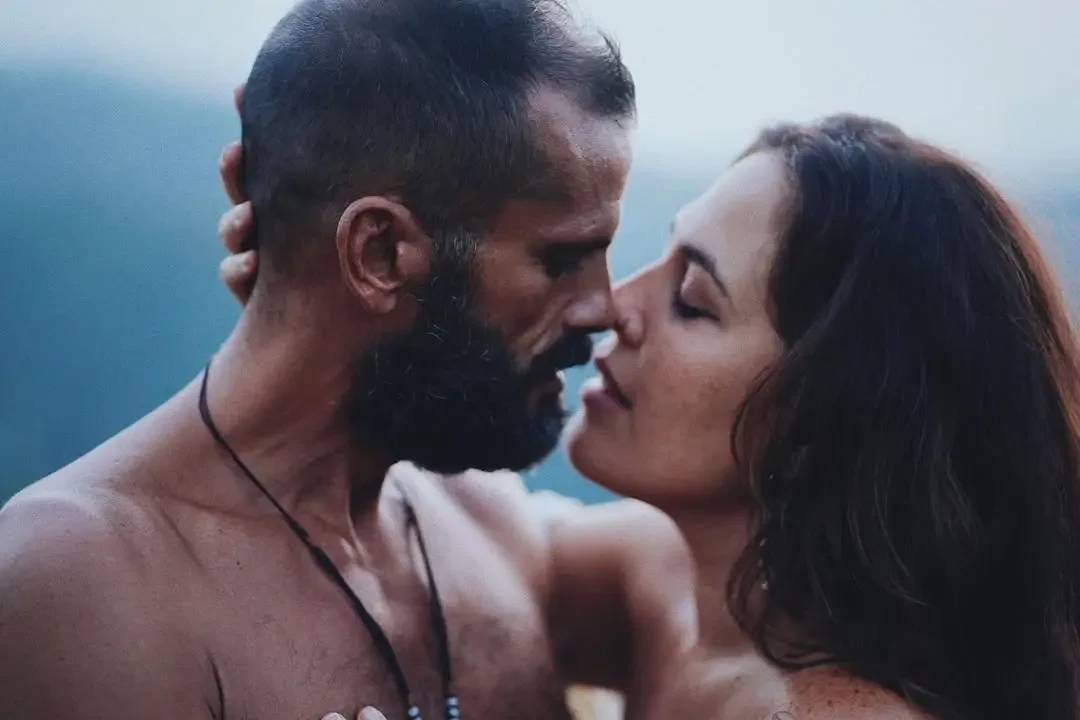 Una pareja está muy cerca, con sus rostros casi tocándose, en un momento íntimo y romántico.