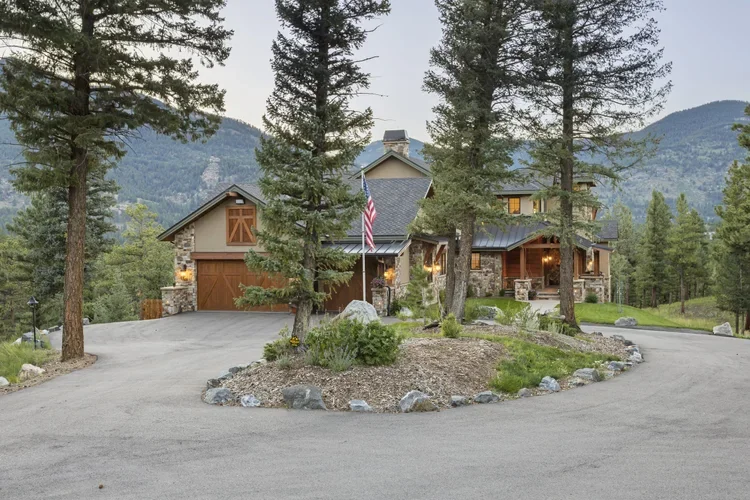 A mountain house with a surrounding forest and driveway