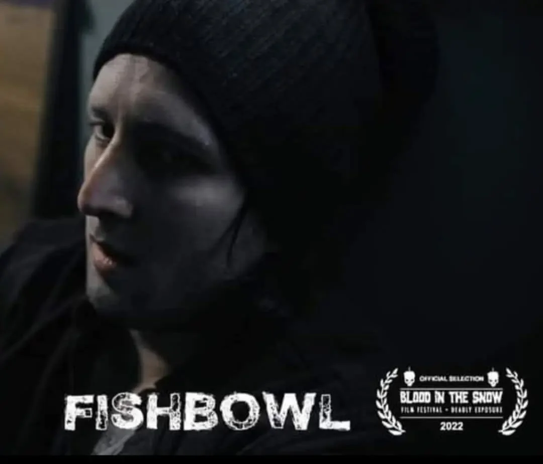 A person with painted makeup on their face wearing a black knit hat, looking to the side, with the words "FISHBOWL" below and a festival logo reading "Blood in the Snow 2022."