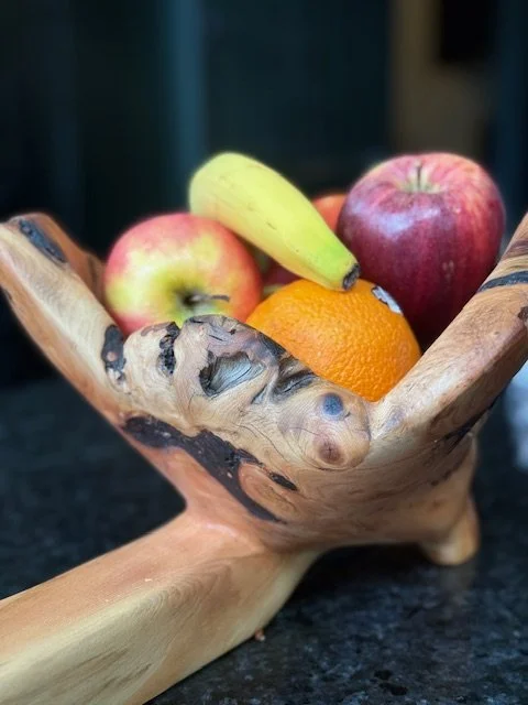 Wooden bowl with apples, a banana, and an orange on a dark surface.