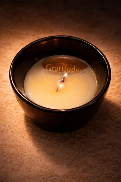 Close-up of a glowing white candle revealing gratitude encouragement stone in the melt pool