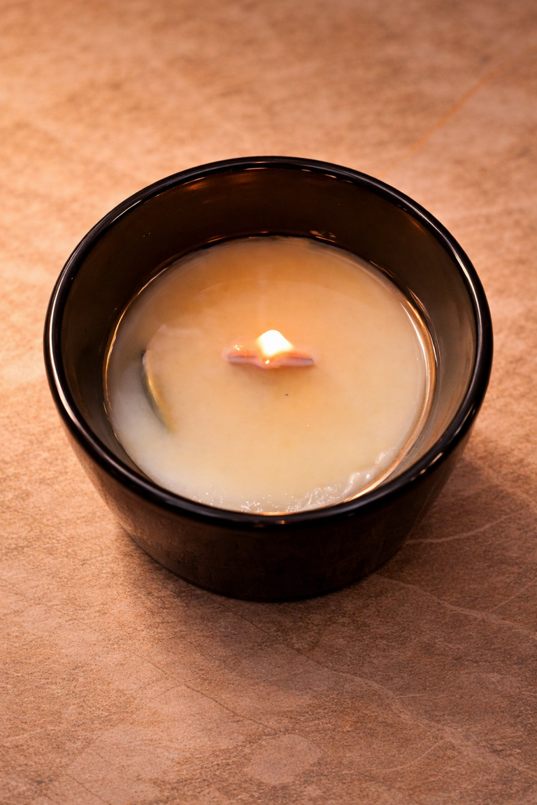 Coconut soy recovery candle with a hidden coin just starting to emerge through the melted wax, shot in soft light for the Recovery & Sobriety collection