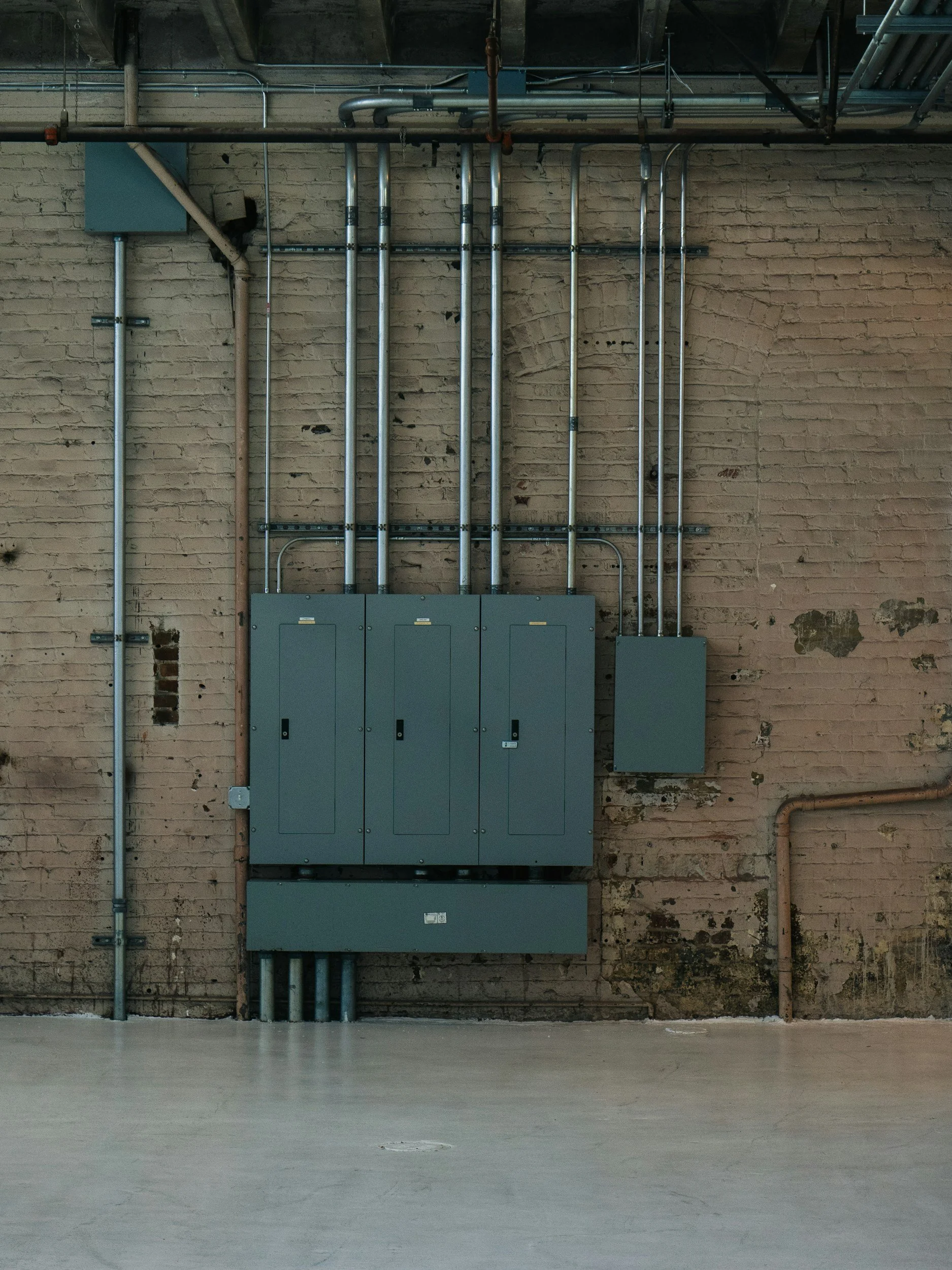 An industrial setting with a brick wall, electrical boxes, and metal pipes.